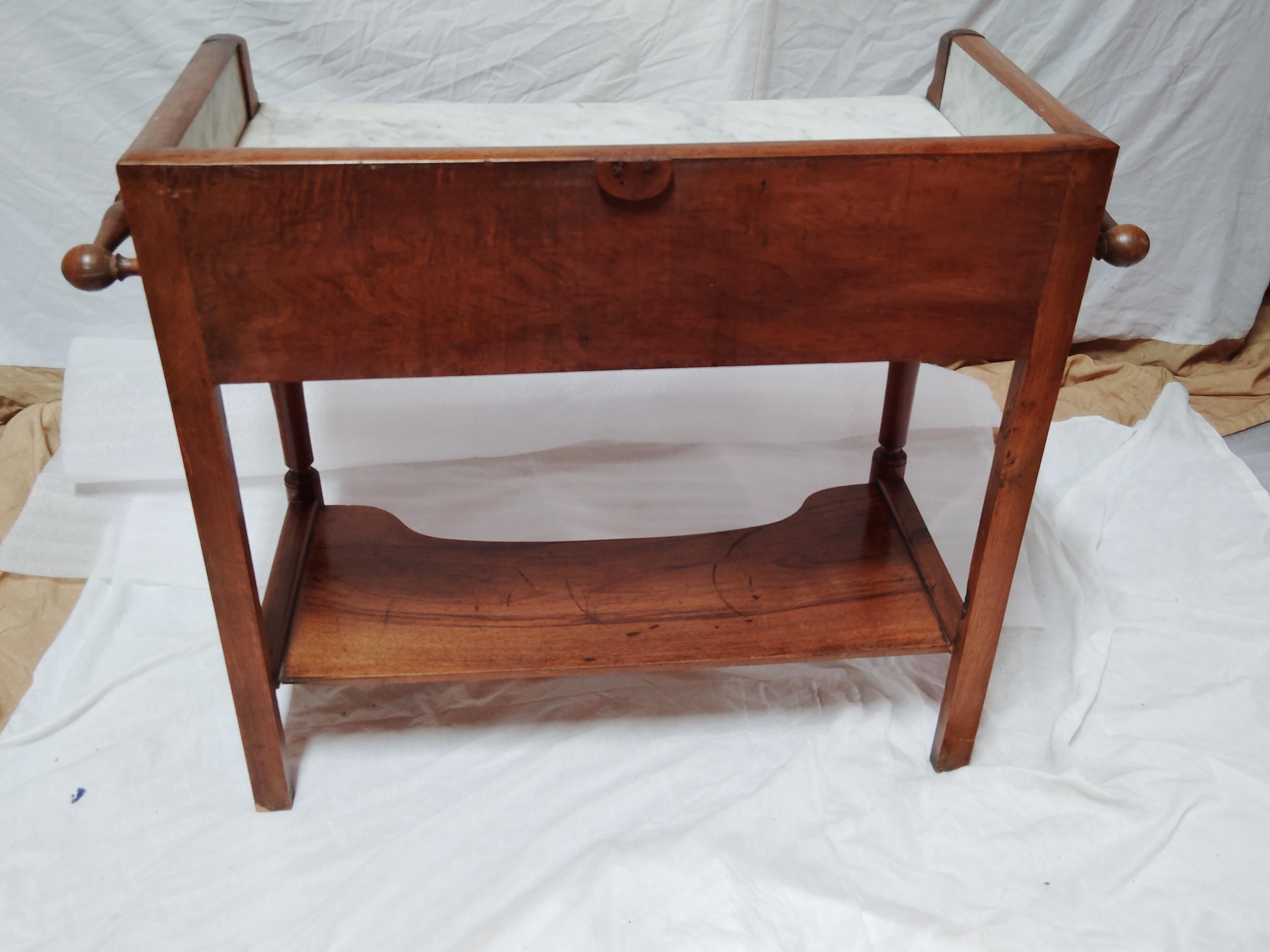 A larger than normal washstand with a captivated white veined marble top and surround. Below the top are two individual full-depth drawers with raised mouldings to the front and turned drawer pulls.
The sharply turned front legs lead down to a