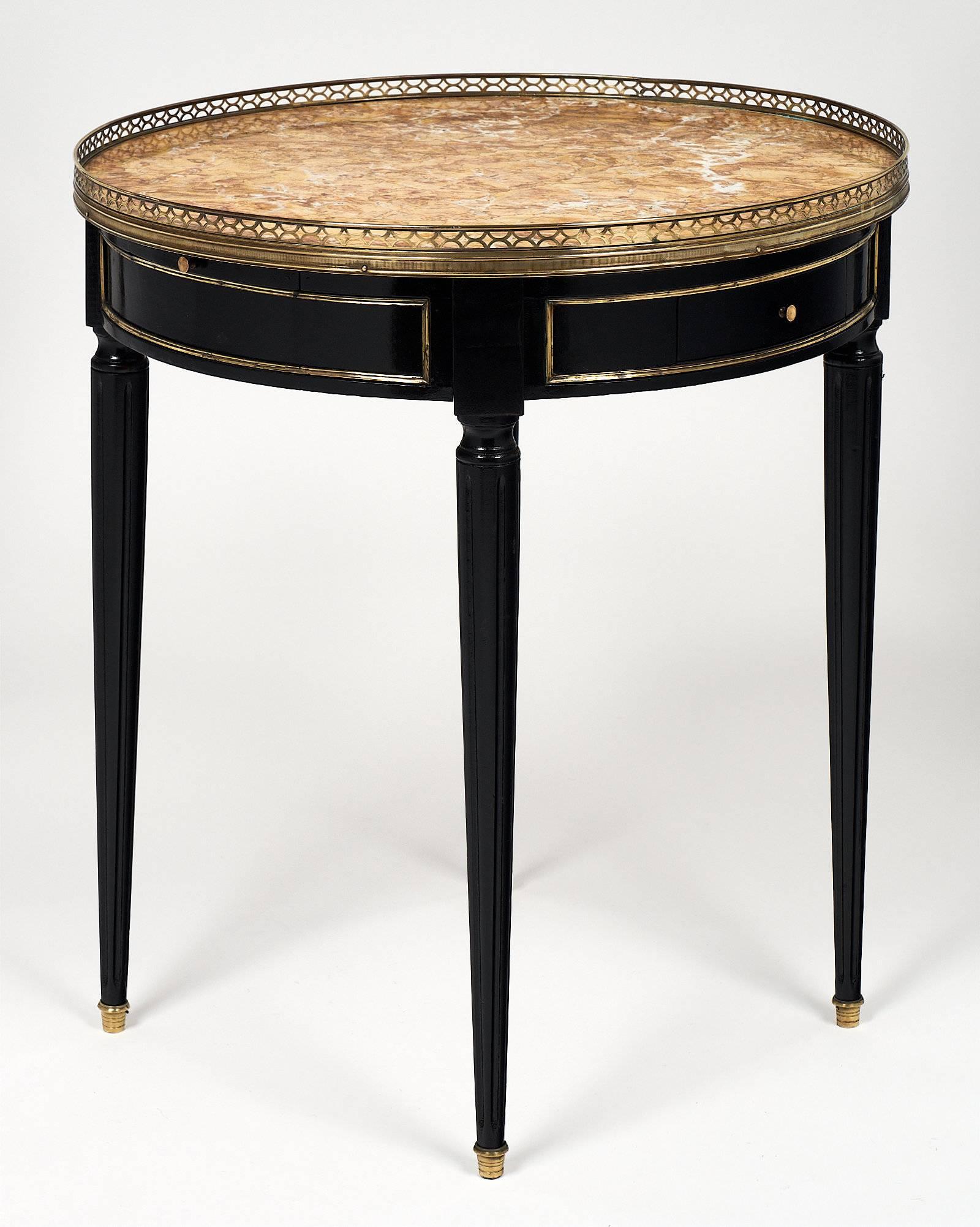 An elegant Louis XVI mahogany side table with a veined gold “brêche D’Alep” marble top. It also features an opened gilt brass gallery; fluted legs with gilt brass feet; and brass trims. With its two drawers and two pull-out shelves; this elegant