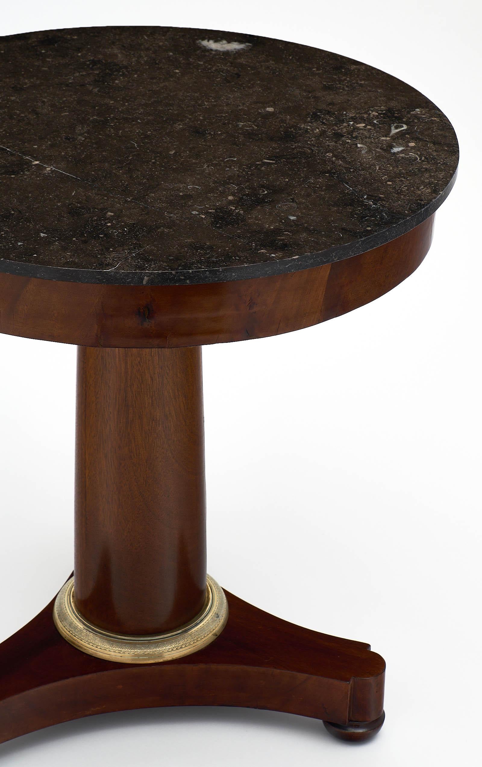 Empire period marble topped gueridon with a Cuban flamed mahogany base, finished with a lustrous French polish. The tripod feet have a finely cast bronze ring for decoration. The original marble top is intact.