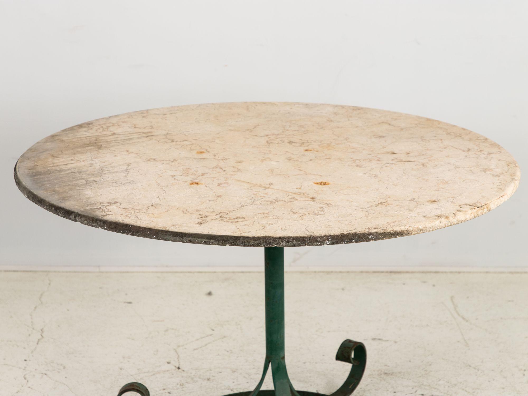 A mid-20th-century French garden or pub table adorned with a luxurious white marble top exudes a timeless charm that marries elegance with rustic allure. Its green-painted base adds a touch of vintage character, reminiscent of quaint French bistros