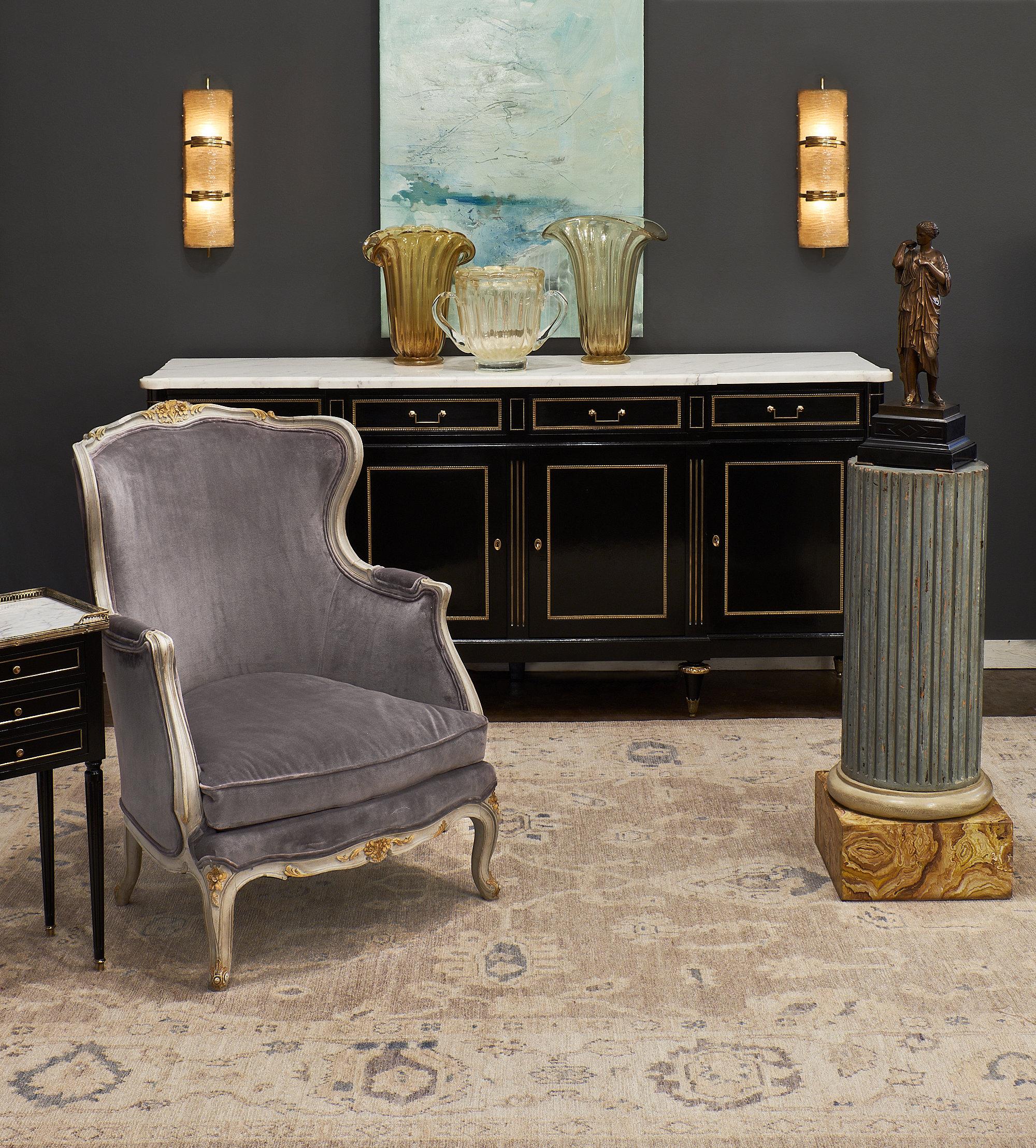 A fine French marble topped Louis XVI style pair of side tables; each featuring three dovetailed drawers trimmed with gilt brass. The tables are made of ebonized mahogany; finished with a lustrous French polish. The Carrara marble tops are protected