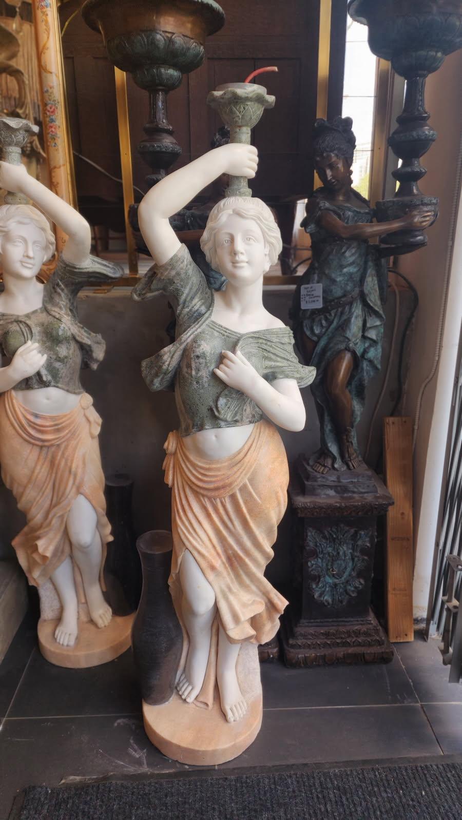 Cette annonce présente une paire de sculptures en marbre de style Art nouveau représentant des figures féminines tenant des torches. L'Art nouveau est un style qui se caractérise par ses formes organiques, ses lignes fluides et ses détails