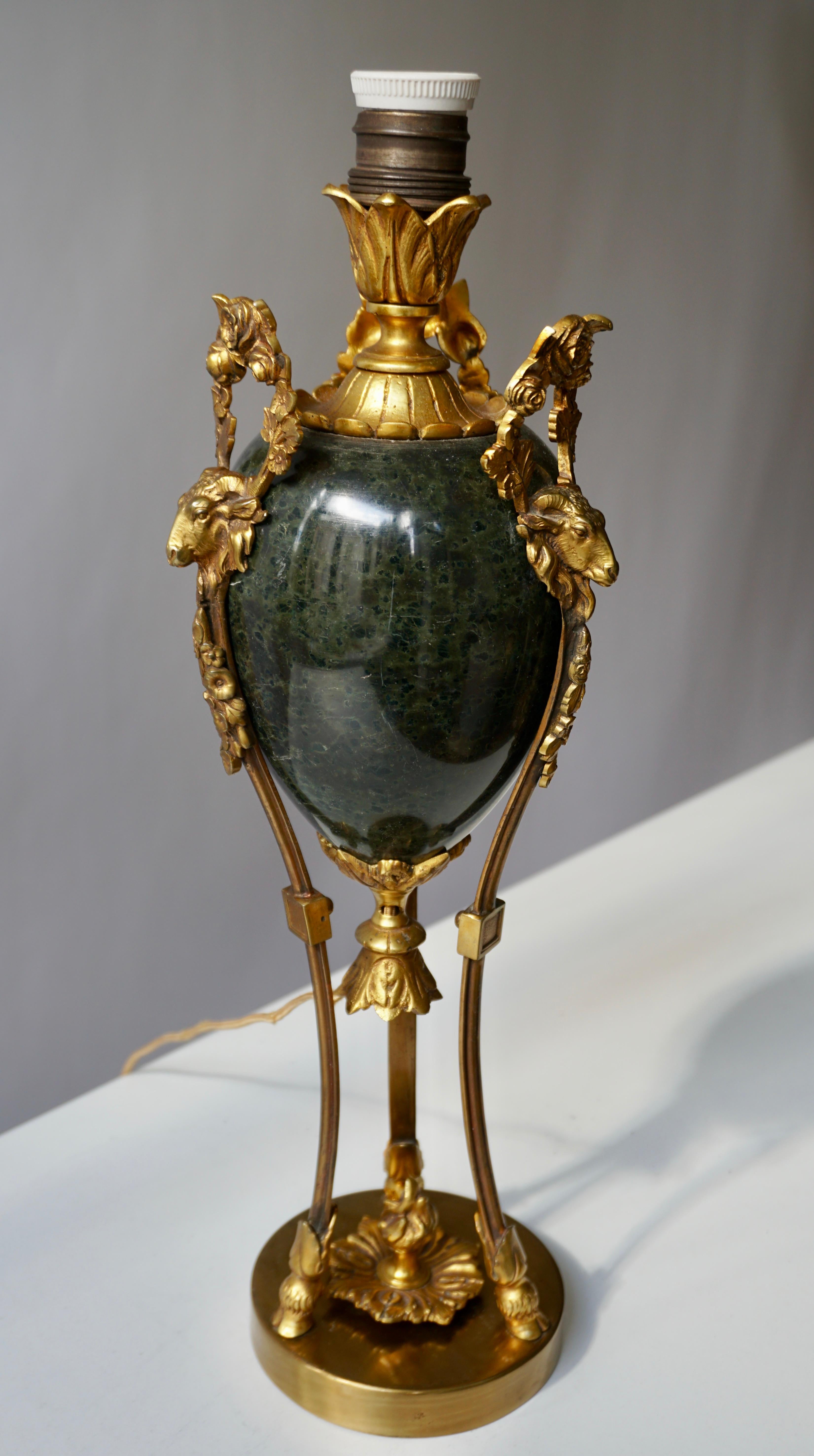 This very fine and heavy black and green marble urn, adorned with bronze rams heads and bronze ormolu, has been crafted into an elegant table lamp. 
Measures: Height 46 cm.
Diameter 14 cm.
Weight 3 kg.