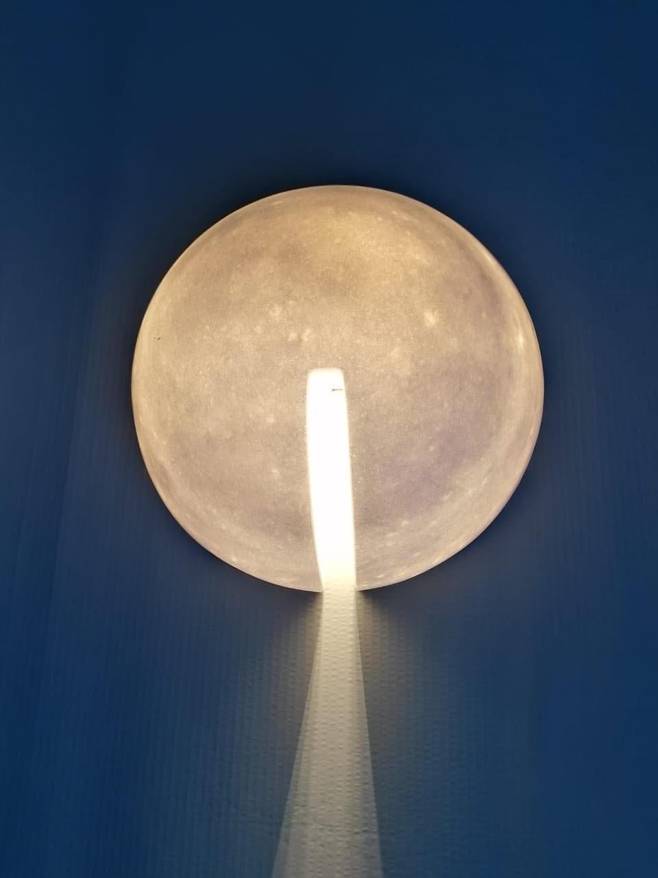 Marble wall lamp by Tom von Kaenel
Dimensions: D 34 cm
Materials: Marble

All the artworks of Tom von Kaenel are unique, handcrafted by himself.
The stones all come from the surrounding marble quarries of the island. The Naxian marble is of