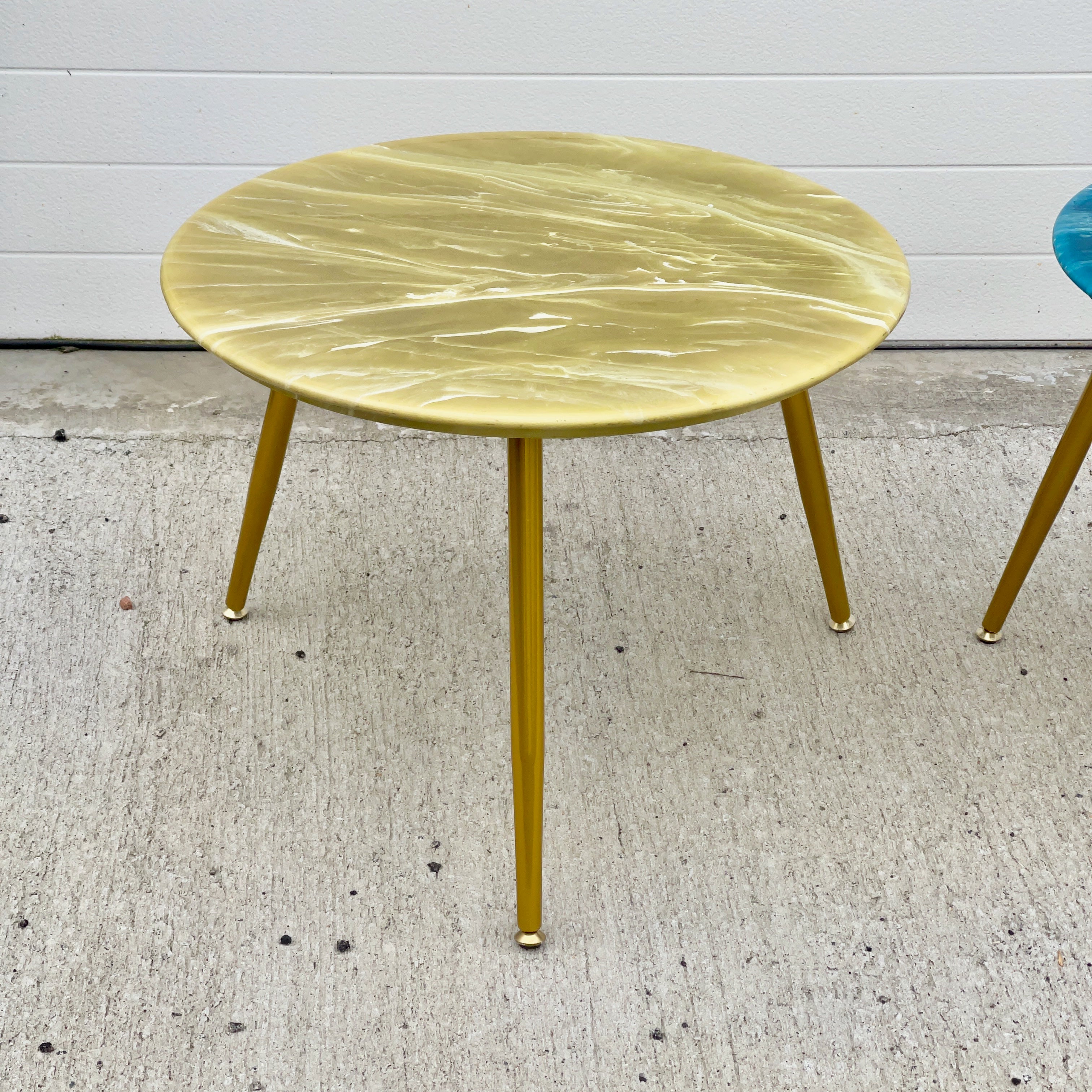 Three legged round top table consisting of a 23 inch diameter simulated onyx resin top by MarbleCraft on three 16 inch tapered brass-tone legs with self-leveling feet.
Both the top and the legs are New Old Stock (NOS) from 1963 and have never been