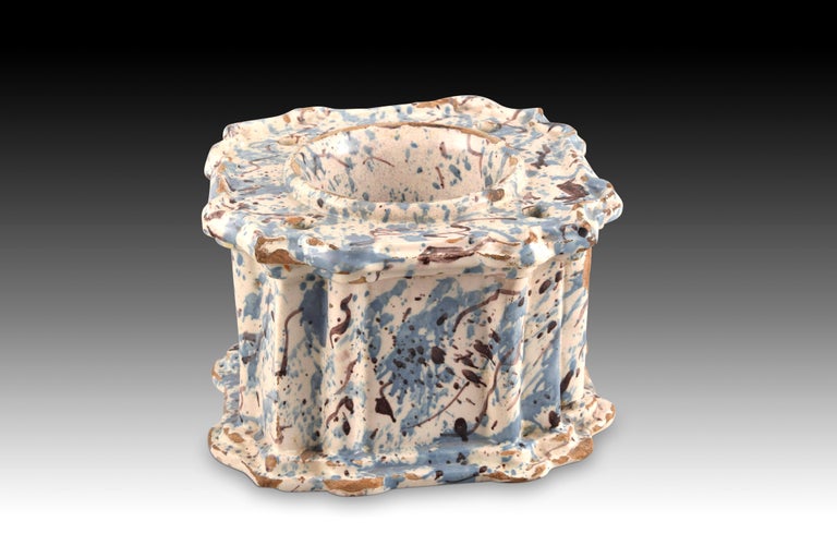 Inkwell, variegated series. Glazed ceramic. Possibly Talavera, 17th century. 
Slightly rectangular inkwell, decorated with two semicircular pillars on each front, made of glazed ceramic with a type known as marbled finish in blue and brown tones. It