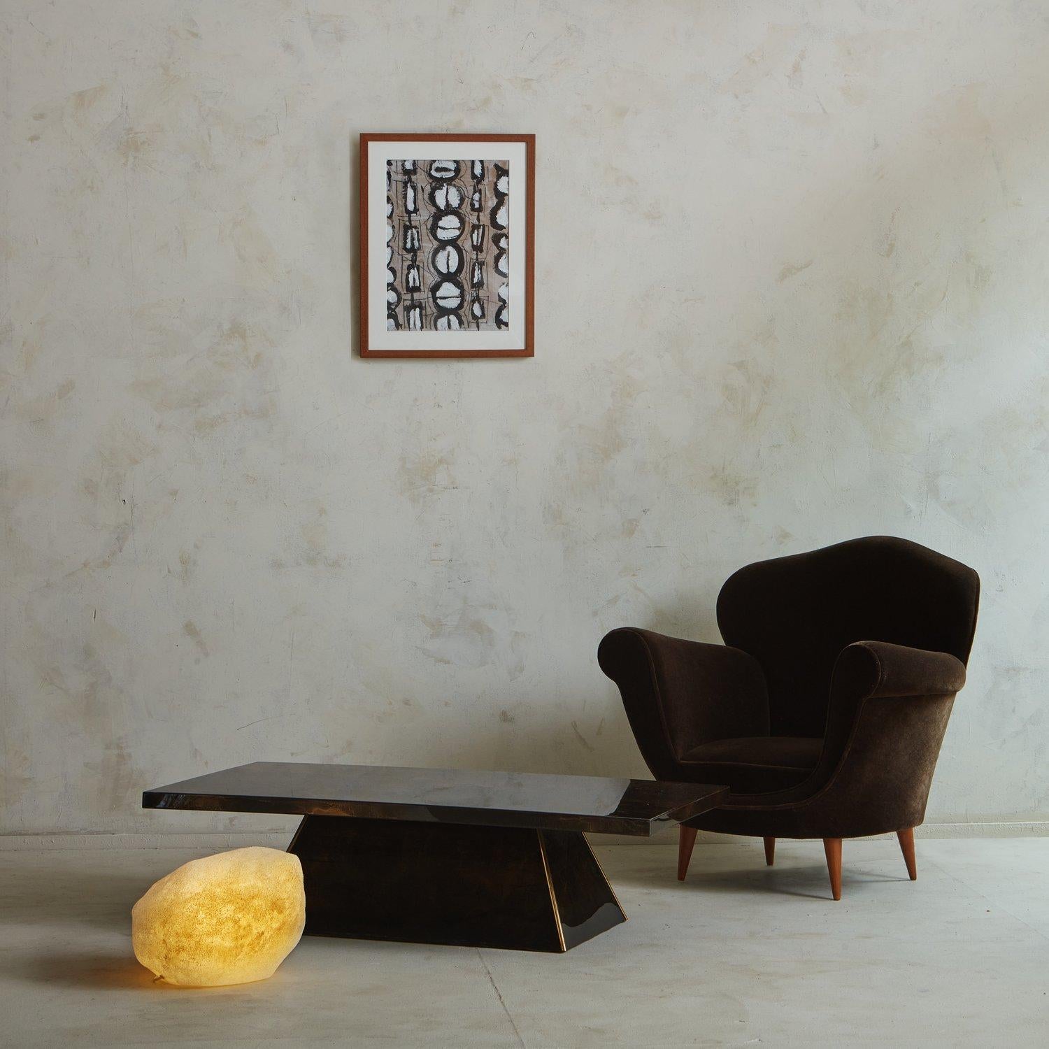 A 1980s French coffee table featuring a captivating marbled brown resin finish. This piece has a handsome angled pedestal base with brass detailing. Unmarked. Sourced in France, 1980s. 