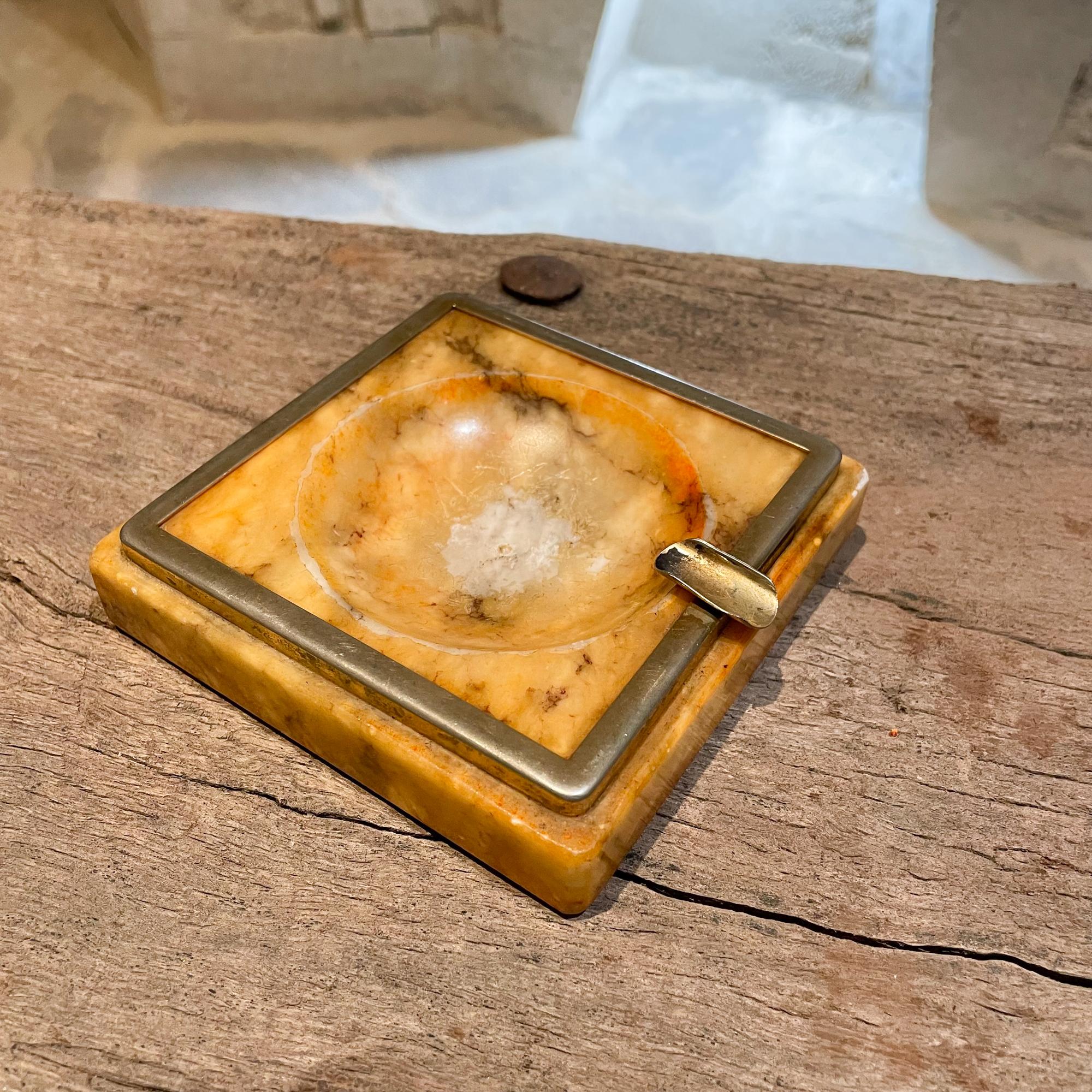 Mexico 1970s Mid-Century Modern Hipster ashtray
Vintage square stone ashtray outlined in brass.
Golden yellowish tones 
Measures: 4.5 x 4.5 x 1 H
Expect Vintage item presentation. Unrestored. Wear Visible. Middle section shows vintage wear.
See