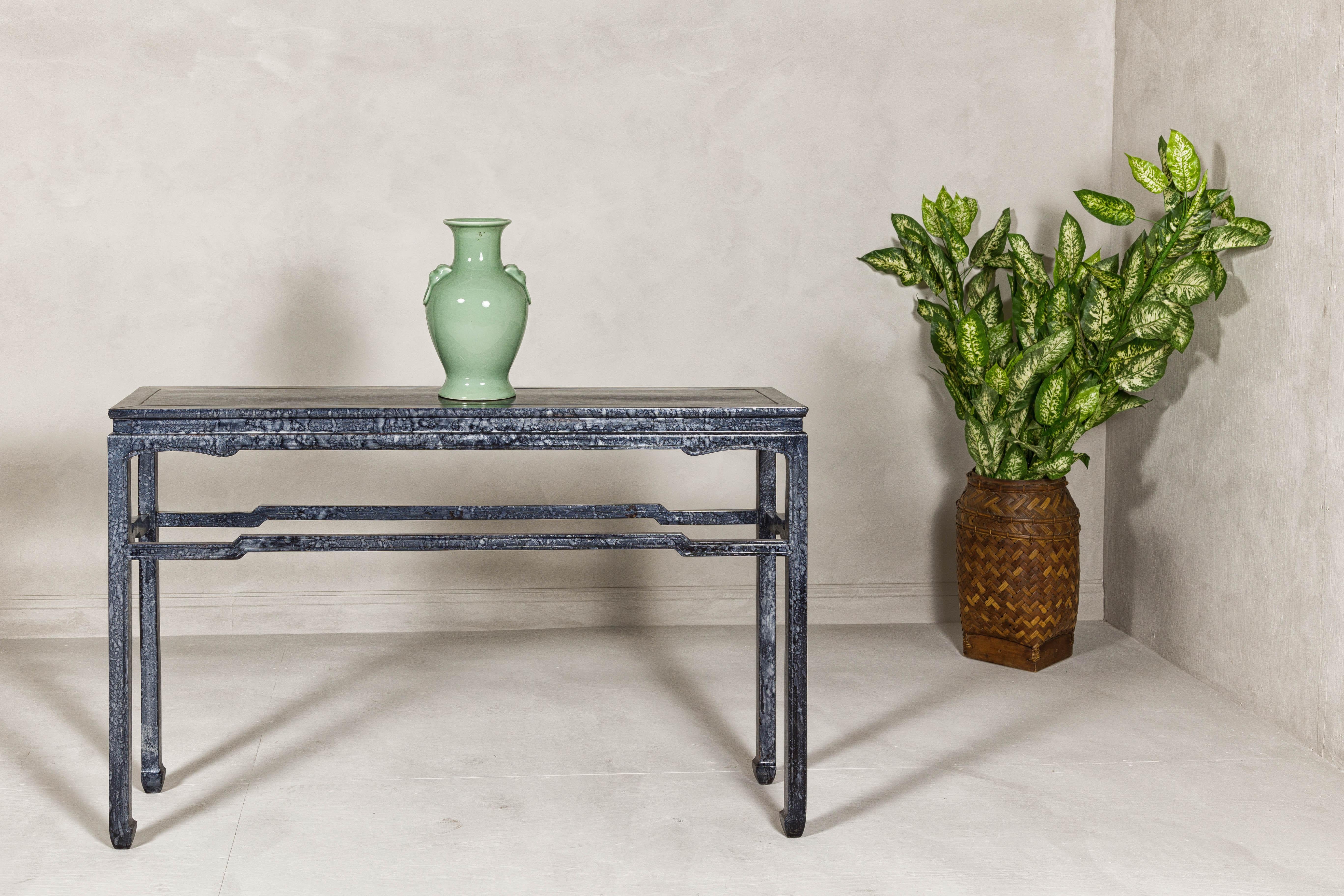 A vintage marbleized console table with black and silver variegated finish, humpback stretcher and horse hoof feet. This marbleized console table exudes refined elegance and a sophisticated presence. The table features a stunning black and silver