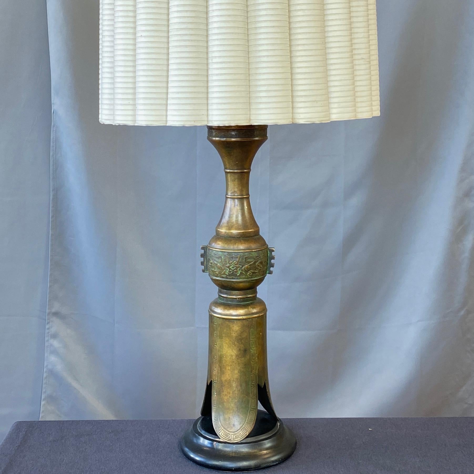 A towering 1950s Chinese archaistic-style brass table lamp by the Marbro Lamp Company, done in the manner of James Mont.

Striking interpretation of a three-footed archaic ritual bronze from the Shang or Zhou dynasties. Such vessels furnished the