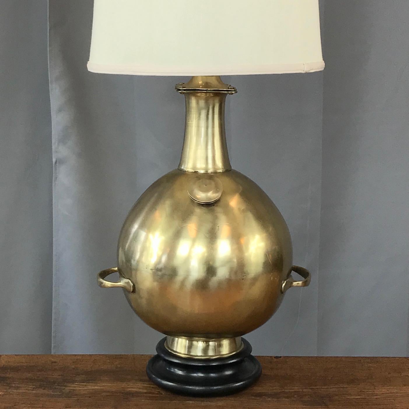 A monumental and uncommon Marbro Lamp Company brass table lamp on black wood base.

Substantial gleaming solid brass body features interesting Machine Age-type design details that evoke an antique diving bell or pressure cooker. Black lacquered