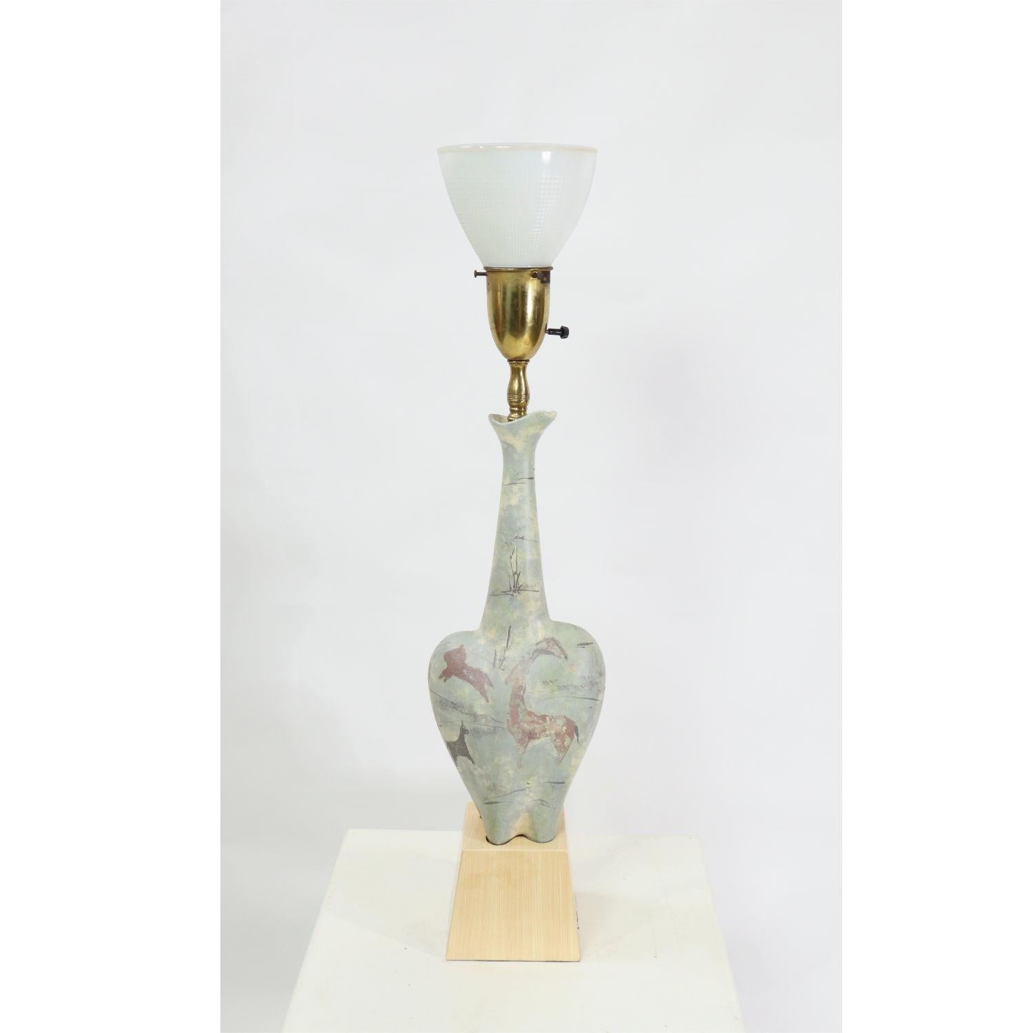This is easily one of the most interesting Mid-Century Modern lamps we’ve come across! Everything about the lamp is unique, from it’s unusual shape to the lip at the top of the bottle neck. The shape mimics a woman’s hips, adorned with Lascaux style