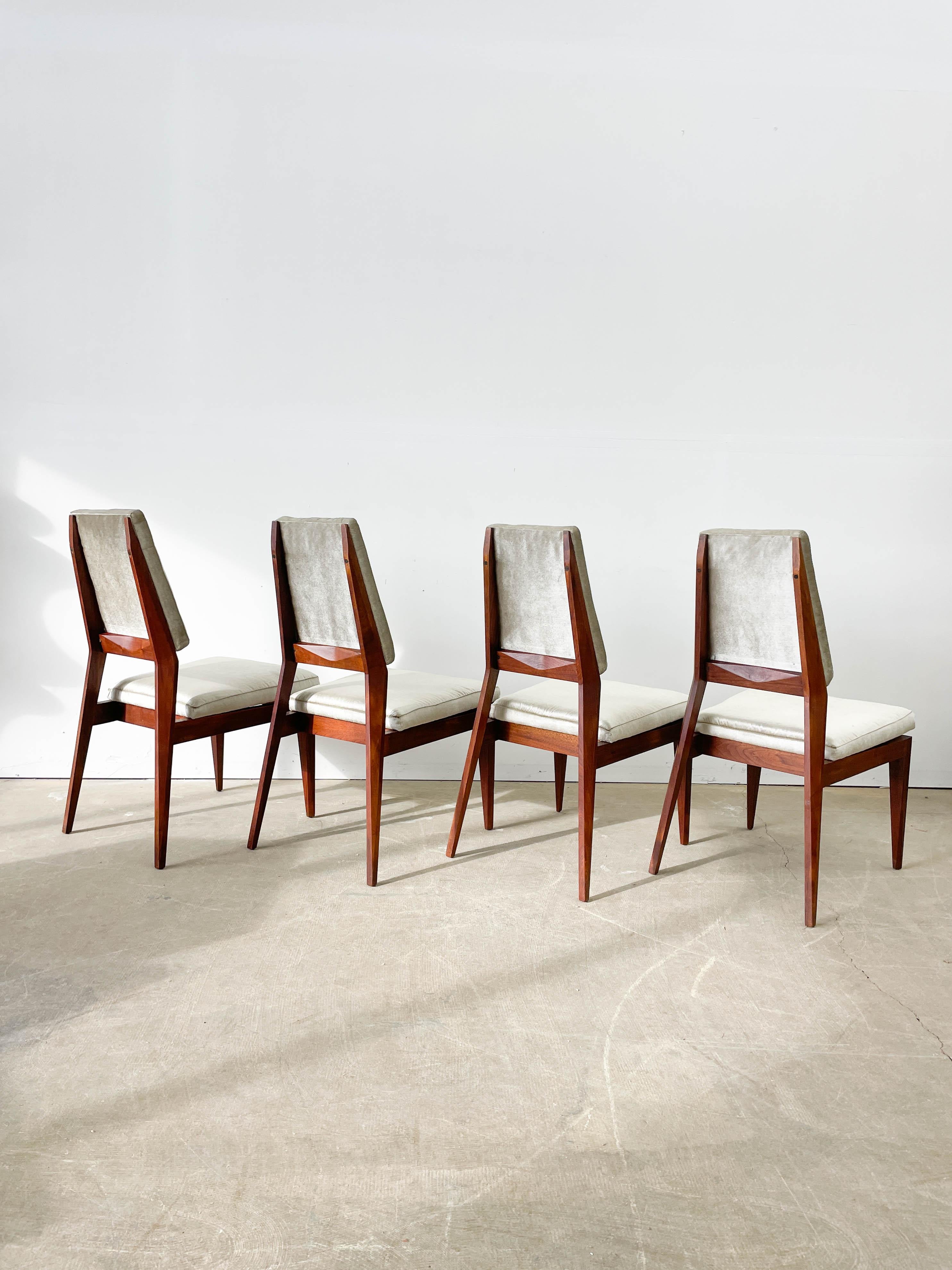 Designed by Marc Berge for Grosfeld House in 1959, these dining chairs have fantastic angular lines and faceted elements that catch the light beautifully. Each of the four chairs is made from solid walnut for a sturdy and attractive foundation. Each