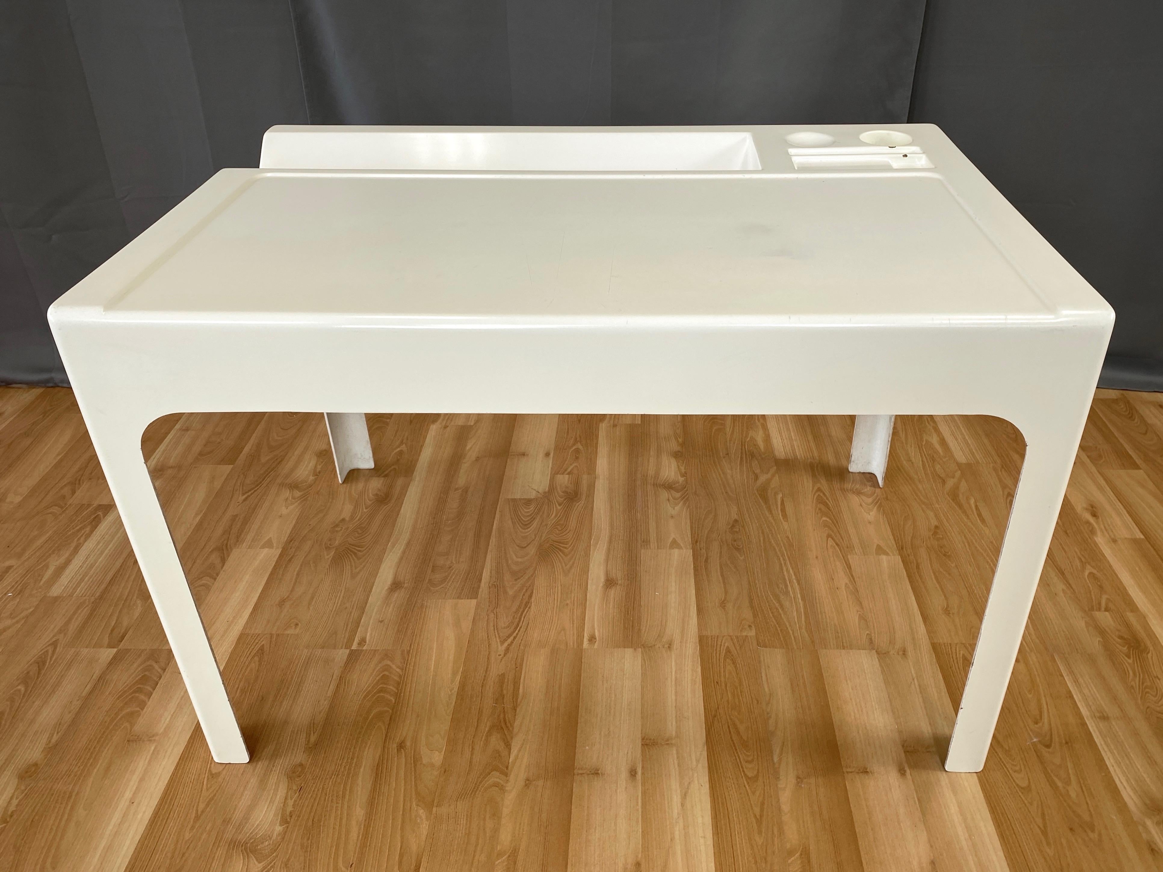A 1967 early production white Ozoo desk by innovative French architect and designer Marc Berthier for D.A.N.

Minimalist unibody fiberglass form with integrated book or magazine trough, pen & pencil cup, and various other recessed spots to hold