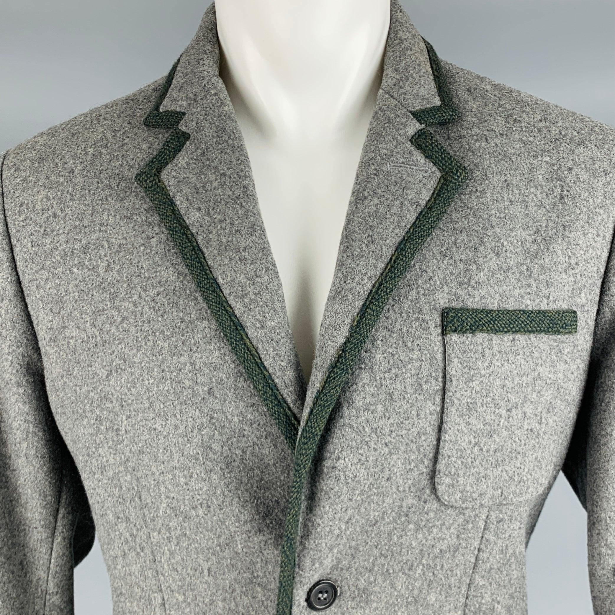 Manteau de sport MARC by MARC JACOBS
 en laine mélangée grise, avec des bordures tissées gris anthracite, un revers échancré, une simple ouverture dans le dos et une fermeture à double bouton. Fabriqué en Pologne. Excellent état. 
 
 Marqué : M 
 
