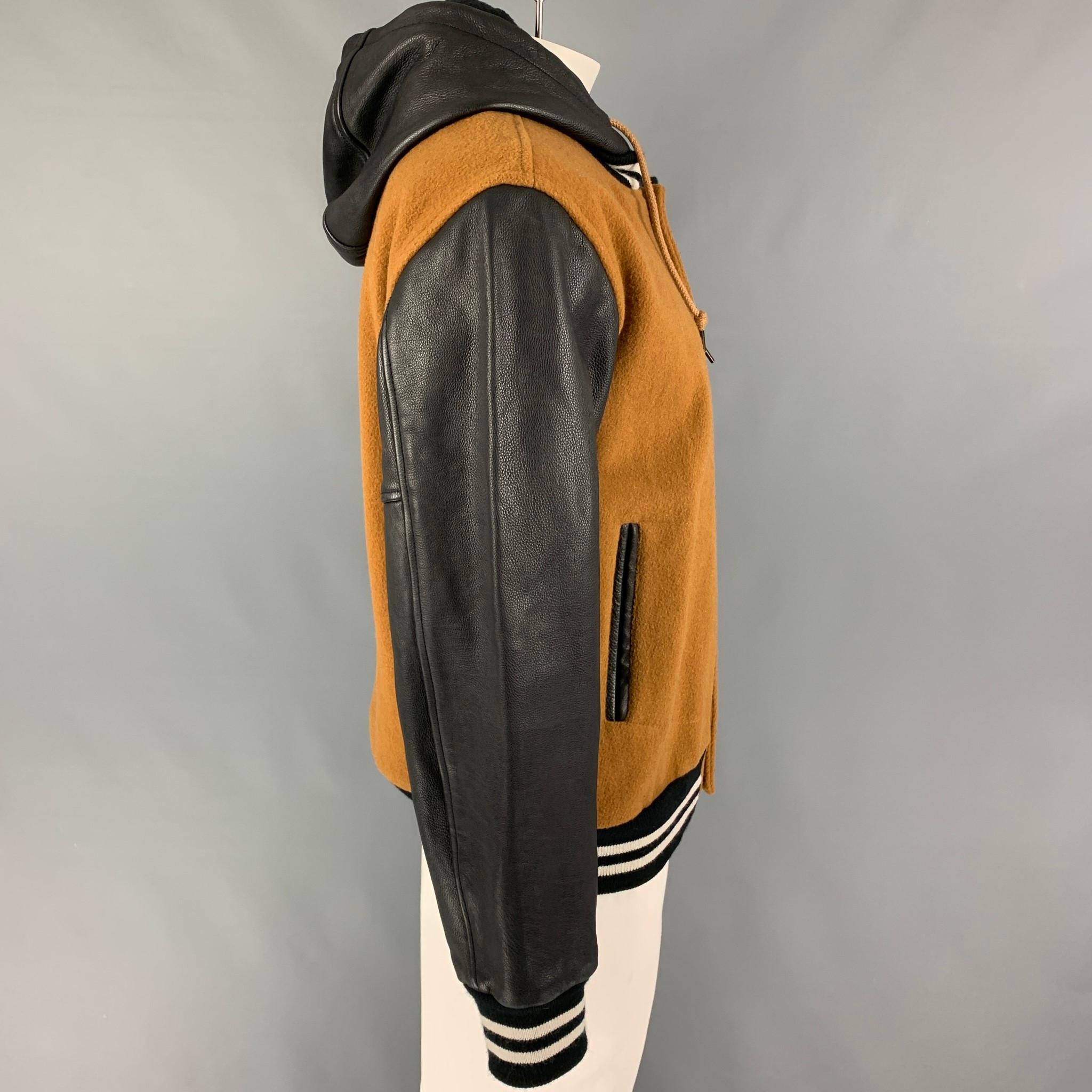 MARC by MARC JACOBS jacket comes in a tan & black mixed materials featuring a varsity style, leather hooded design, ribbed hem, slit pockets, leather sleeves, and a snap button closure. 

Very Good Pre-Owned Condition.
Marked: