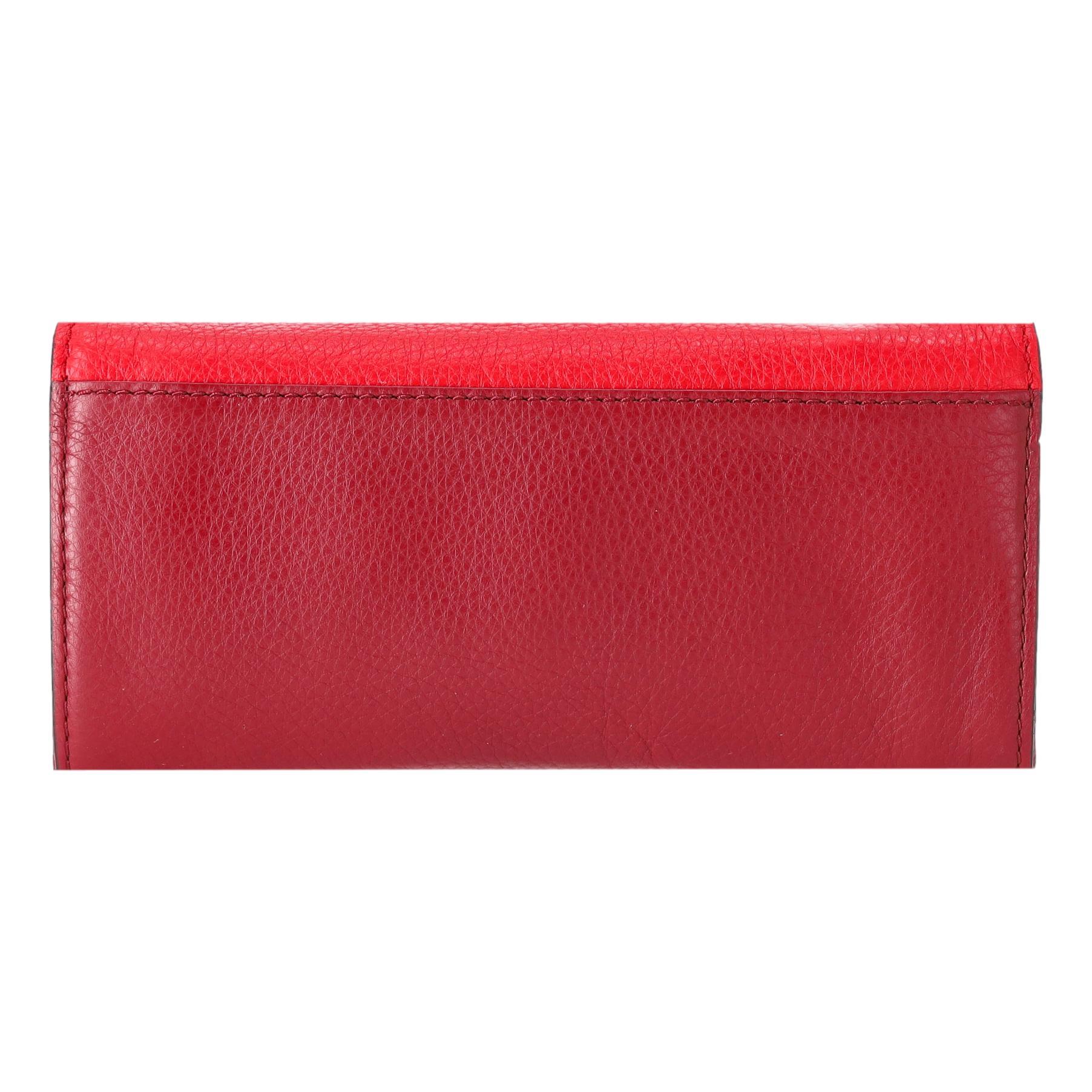 Marc by Marc Jacobs Zweifarbige kontinentale Geldbörse aus Leder

Burgunderrote, lange Brieftasche mit roter Klappe, die mit einer goldenen Plakette mit geprägtem Branding versehen ist.

Mit Druckknopfverschluss, der zu einem Innenraum mit zwei