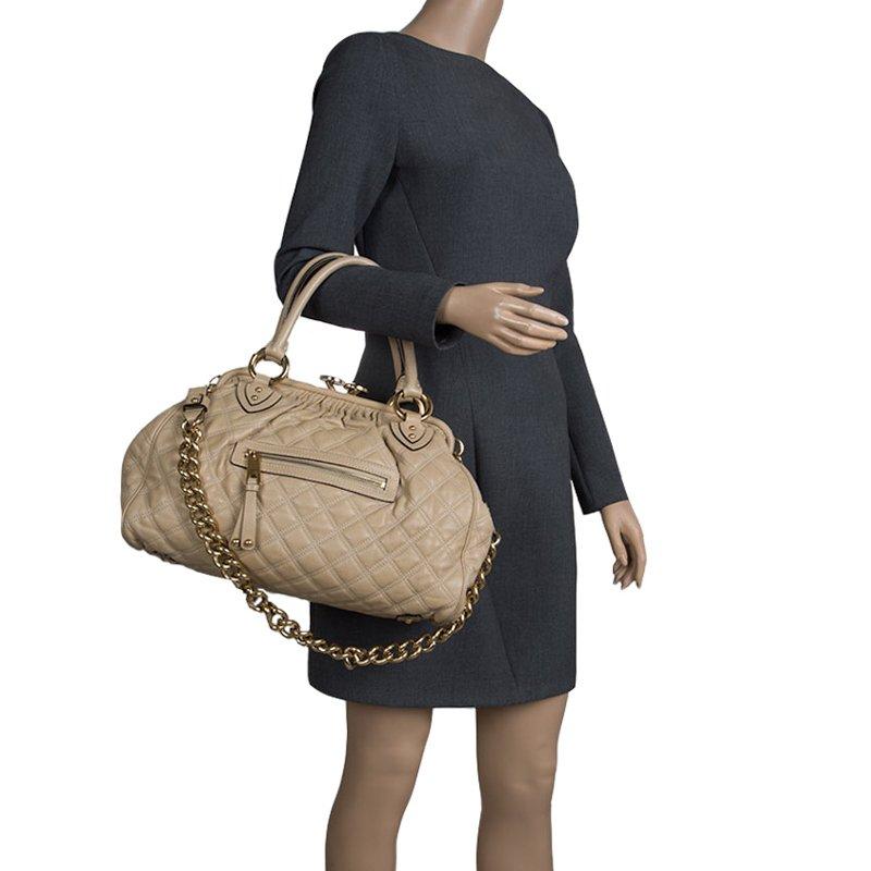 This Marc Jacobs design has a beige quilted exterior crafted from leather, and gold-tone hardware. This elegant Stam bag features a kiss-lock top closure that opens to a fabric interior, dual top handles and a removable chain that converts this