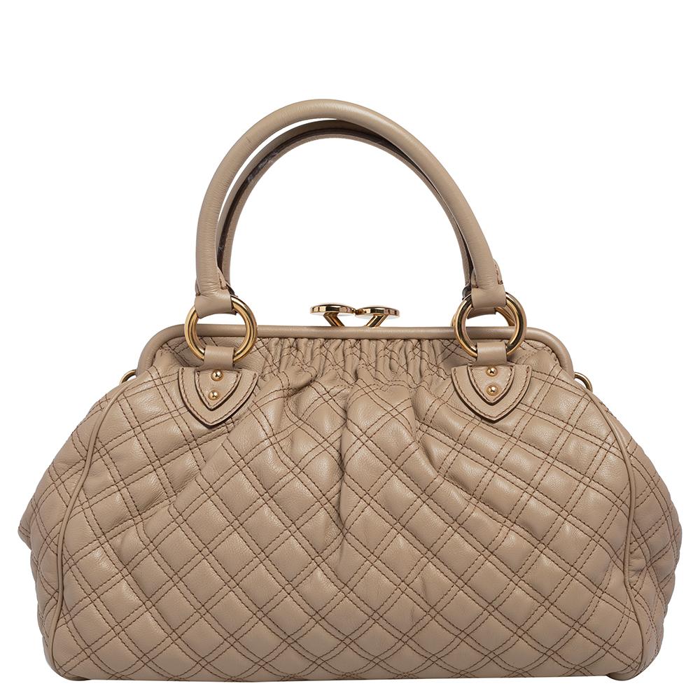 This Marc Jacobs design has a beige quilted exterior crafted from leather and enhanced with gold-tone hardware. This elegant Stam bag features a kiss-lock top closure that opens to a fabric interior, dual top handles, and a removable chain that