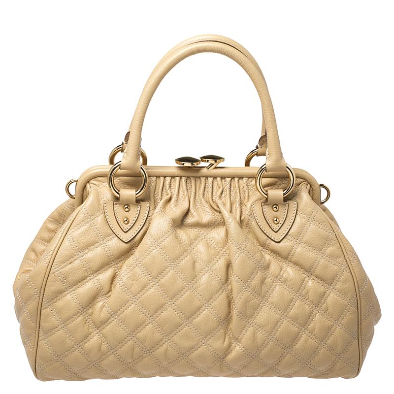 This Marc Jacobs design has a beige quilted exterior crafted from leather and enhanced with gold-tone hardware. This elegant Stam bag features a kiss-lock top closure that opens to a fabric interior, dual top handles and a removable chain that