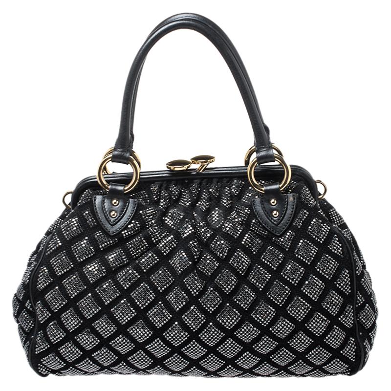 This Marc Jacobs design has a black quilted exterior crafted from suede and enhanced with gold-tone hardware and crystals. This elegant Stam bag features a kiss-lock top closure that opens to a fabric interior, dual top handles and a removable chain