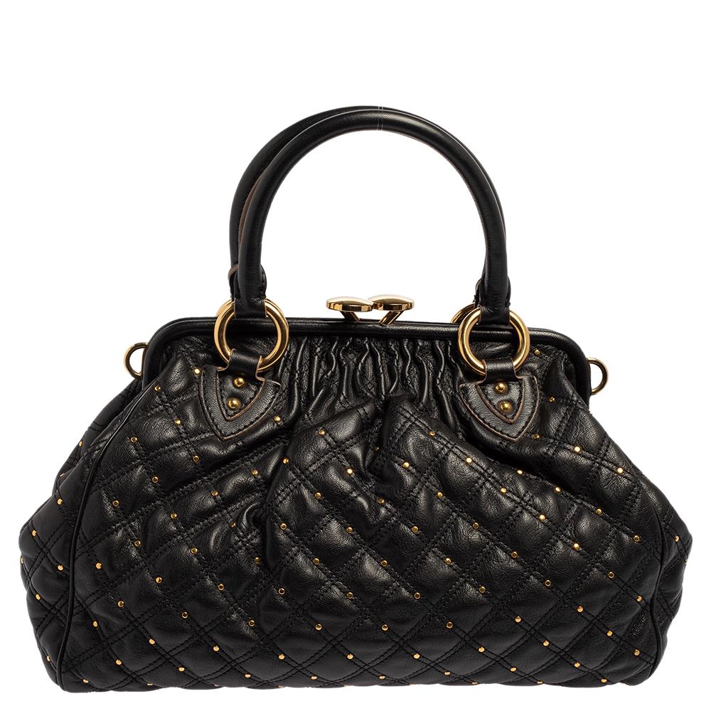 This Marc Jacobs design has a black quilted exterior crafted from leather and enhanced with gold-tone stud embellishments all over. This elegant Stam bag features a kiss-lock top closure that opens to a fabric interior, dual top handles, and a