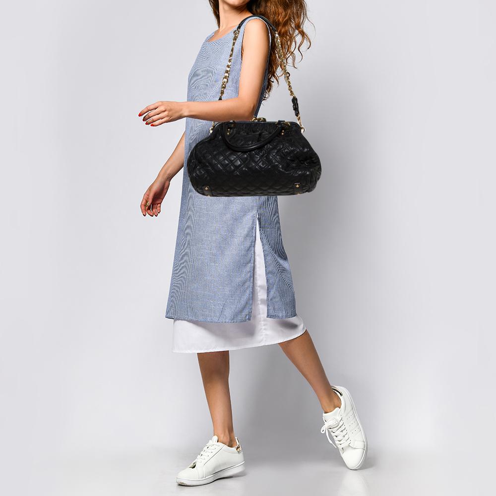This Marc Jacobs design has a black quilted exterior crafted from leather and enhanced with gold-tone hardware. This elegant Stam bag features a kiss-lock top closure that opens to a fabric interior, dual top handles, and a removable chain that