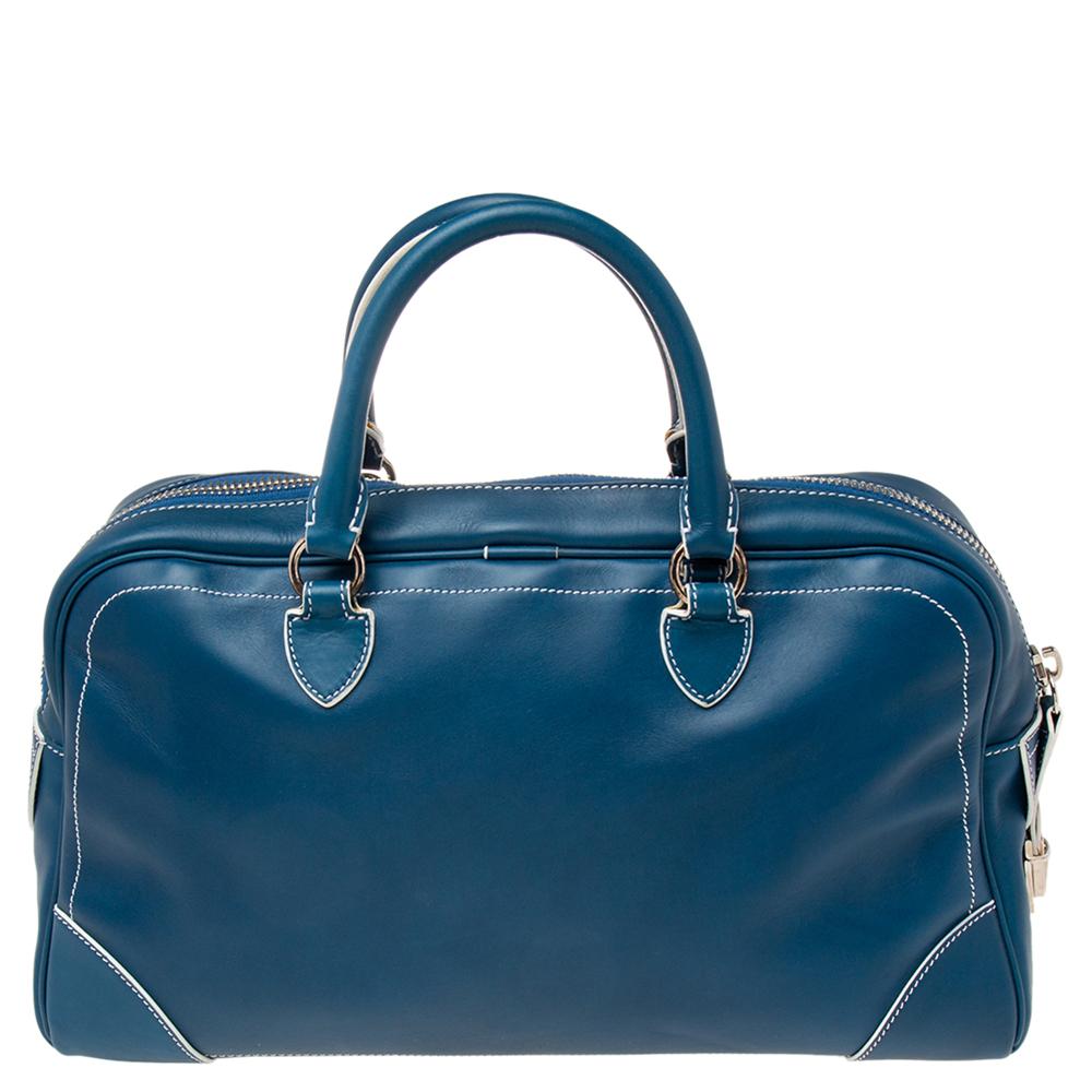 This 'The Venetia' bowler bag from the House of Marc Jacobs is great to appear stylish and trendy! It is made from blue leather on the exterior. It features a spacious canvas-lined interior, silver-tone hardware, and top handles. It is provided with