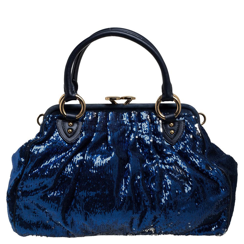This Marc Jacobs design has a blue exterior covered in sequins and enhanced with gold-tone hardware. This elegant Stam bag features a kiss-lock top closure that opens to a satin interior, dual top handles, and a removable chain that converts this