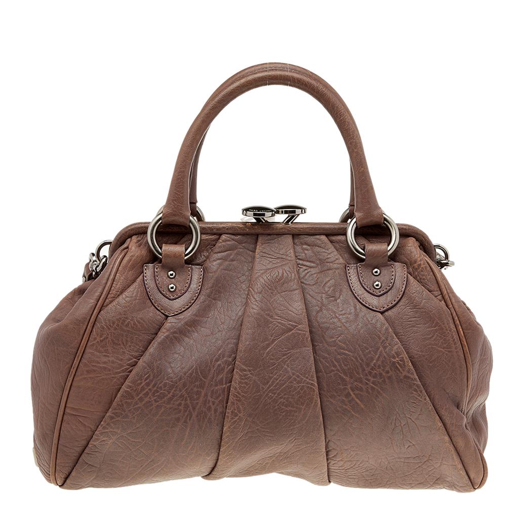This Marc Jacobs design has a brown exterior crafted from leather and enhanced with silver-tone hardware. This elegant Stam bag features a kiss-lock top closure that opens to a fabric interior, dual top handles, and a chain that converts this piece