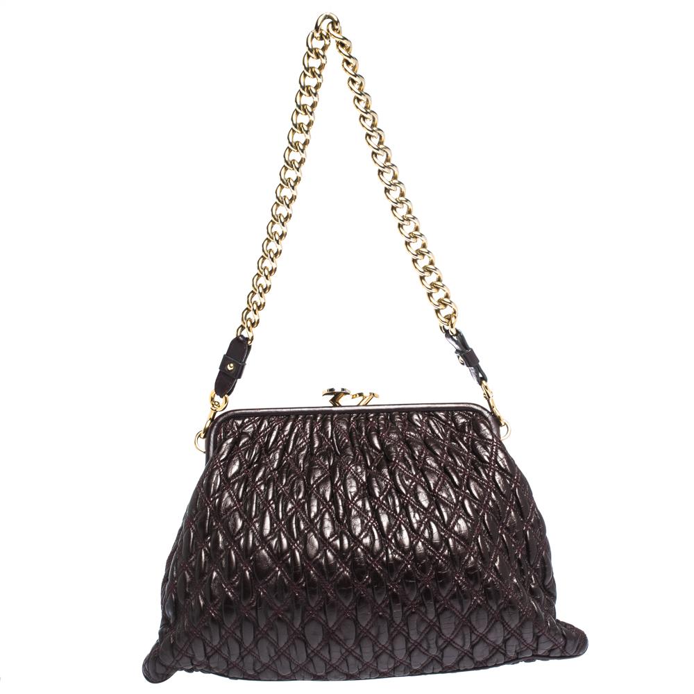 This Marc Jacobs design has a burgundy quilted exterior crafted from leather and enhanced with gold-tone hardware. This elegant Stam bag features a kiss-lock top closure that opens to a fabric interior, dual top handles and a removable chain that