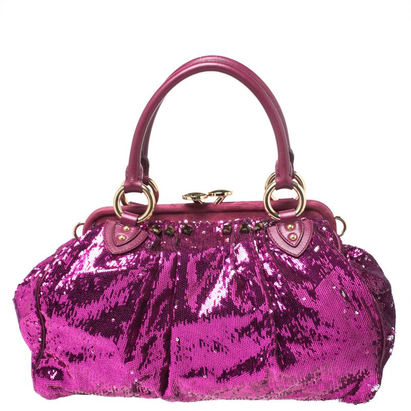 This Marc Jacobs design has a fuchsia exterior crafted from sequins and enhanced with gold-tone hardware. This elegant Stam bag features a kiss-lock top closure that opens to a satin interior, dual top handles and a removable chain strap that