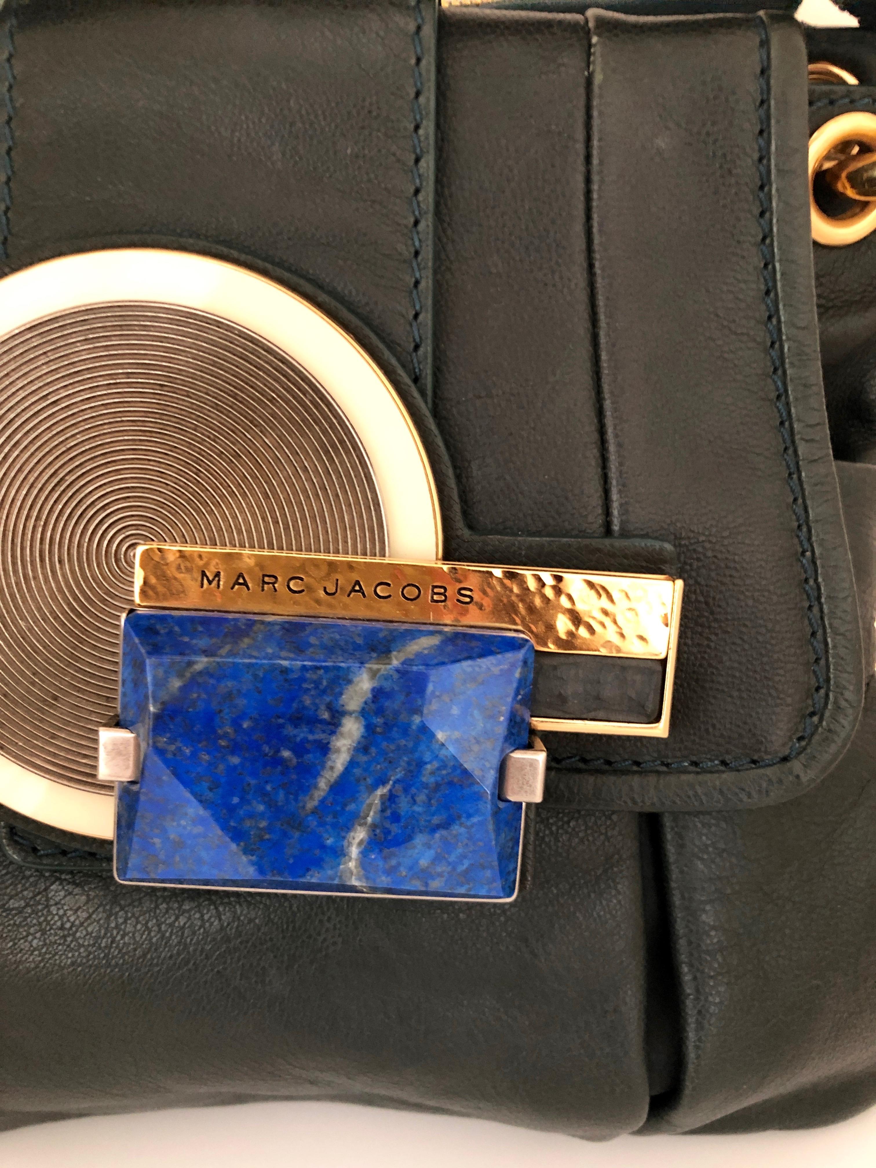 Make:  Marc Jacobs
Place of Manufacture:  Italy
Materials:  Leather, metal and lapis
Color:  Hunter green, gold and lapis blue
Style:  Hunter green ruff hewn leather Paloma double saddlebag with top handle and gold metal accents.  The closure is of