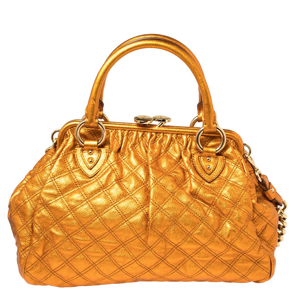 This Marc Jacobs design has a metallic orange quilted exterior crafted from leather and enhanced with gold-tone hardware. This elegant Stam bag features a kiss-lock top closure that opens to a fabric interior, dual top handles, and a removable chain
