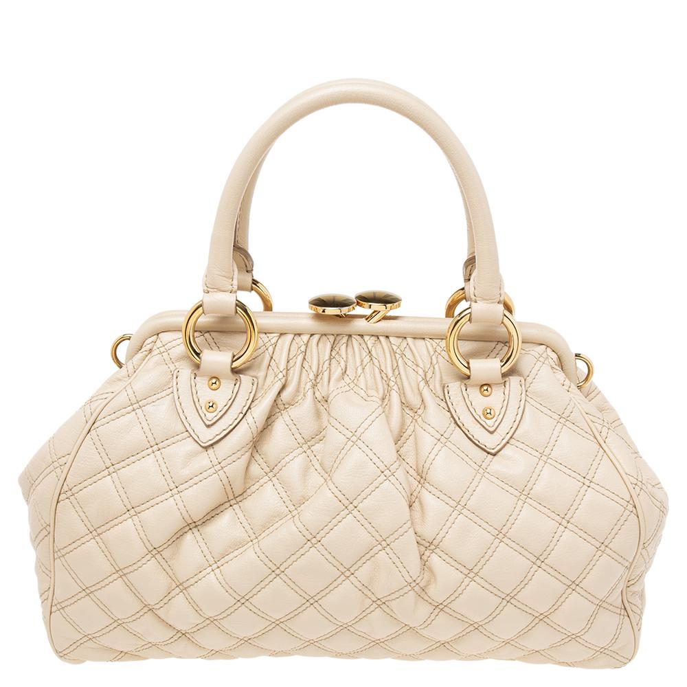 This Marc Jacobs design has an off-white quilted leather exterior that is enhanced with gold-tone hardware. This elegant Stam satchel features a kiss-lock top closure that opens to a fabric interior and has dual top handles and a removable chain