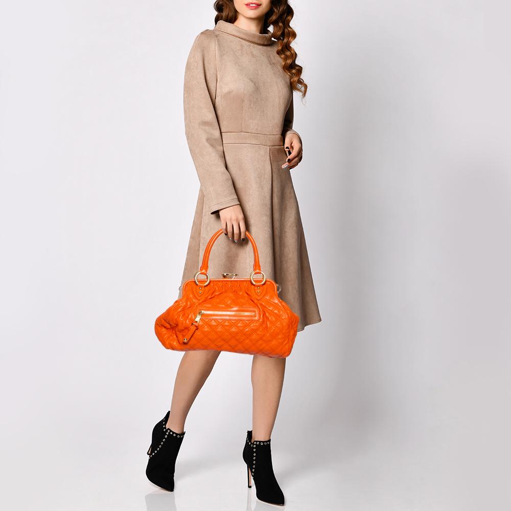 This Marc Jacobs design has an orange quilted exterior crafted from leather and enhanced with gold-tone hardware. This elegant Stam bag features a kiss-lock top closure that opens to a fabric interior, and dual top handles to hold the bag in the