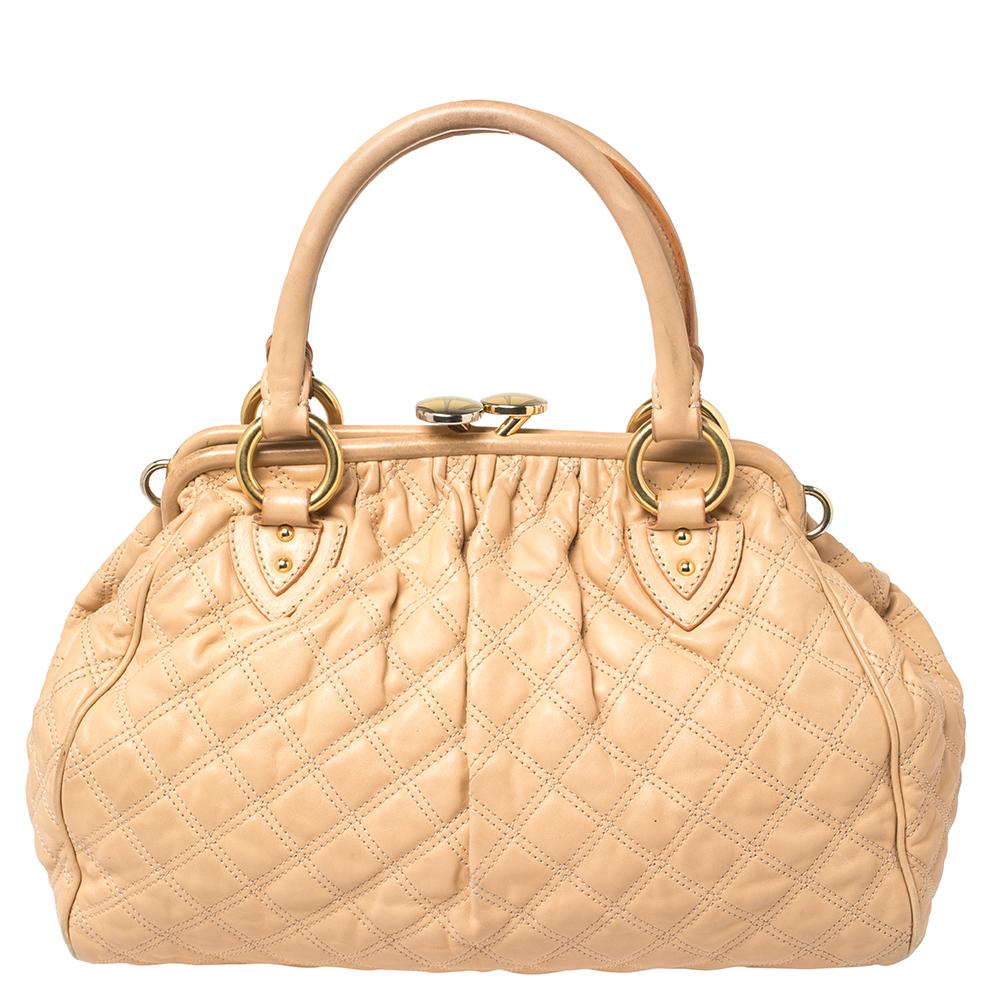 This Marc Jacobs design has a peach quilted exterior crafted from leather and enhanced with gold-tone hardware. This elegant Stam bag features a kiss-lock top closure that opens to a fabric interior, dual top handles, and a removable chain that