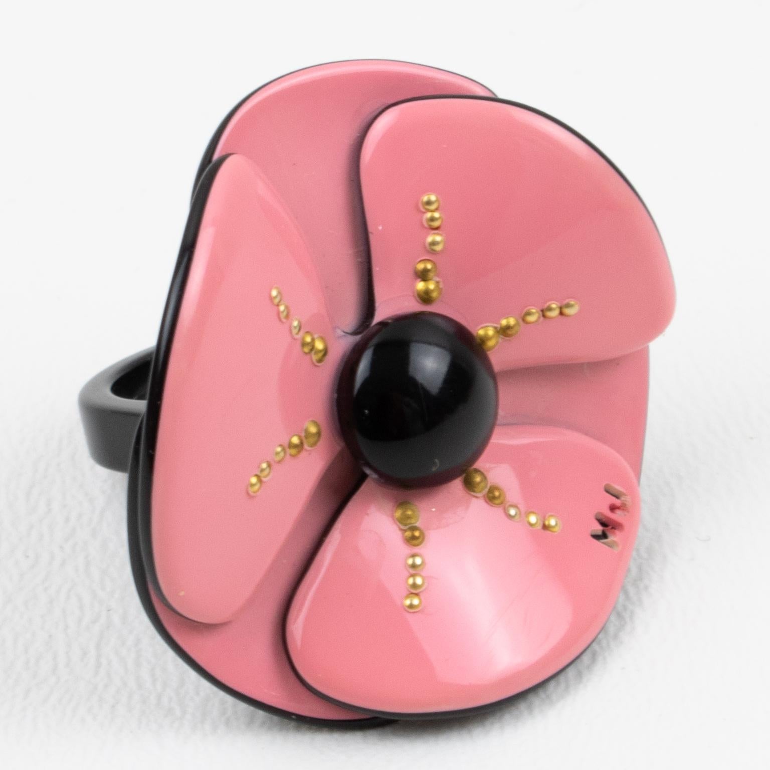 This stunning dimensional fashion ring by Marc Jacobs has a floral-inspired flair. It is made of lightweight resin featuring a wide poppy flower with a black heart and brass stud accents. The piece boasts an elegant palette of powder pink and black