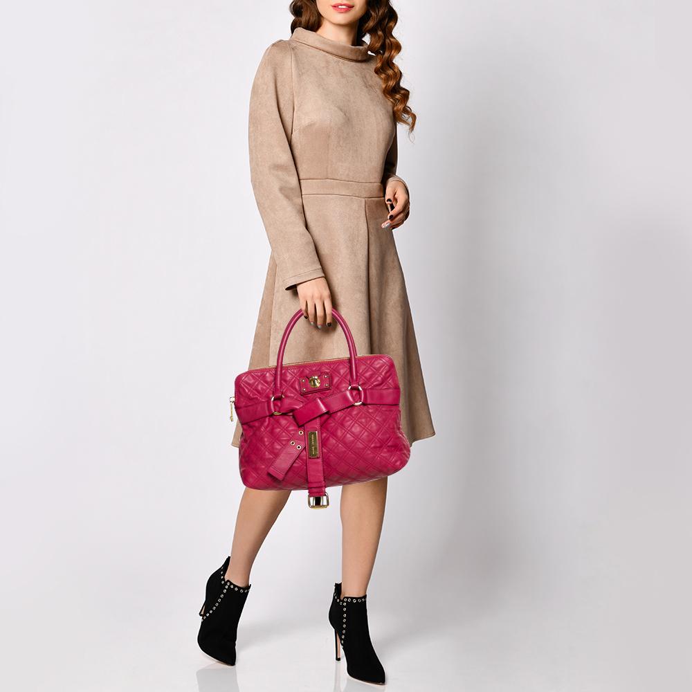 This satchel from Marc Jacobs is an outstanding bag that comes crafted from pink quilted leather and has dual top handles and a gold-tone push-lock and a wide buckle bow detail on the front. It boasts of a nylon-lined interior that has enough space