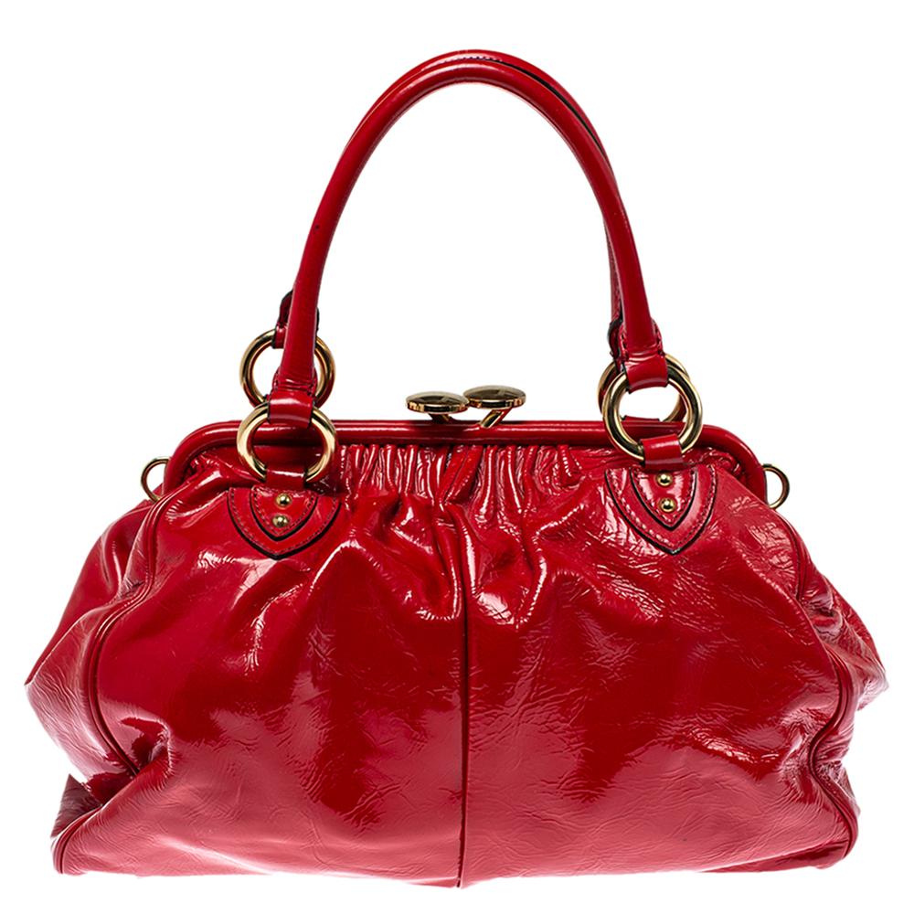 This Marc Jacobs design has a red quilted exterior crafted from patent leather and enhanced with gold-tone hardware. This elegant Stam bag features a kiss-lock top closure that opens to a satin interior, dual top handles, and a removable chain that