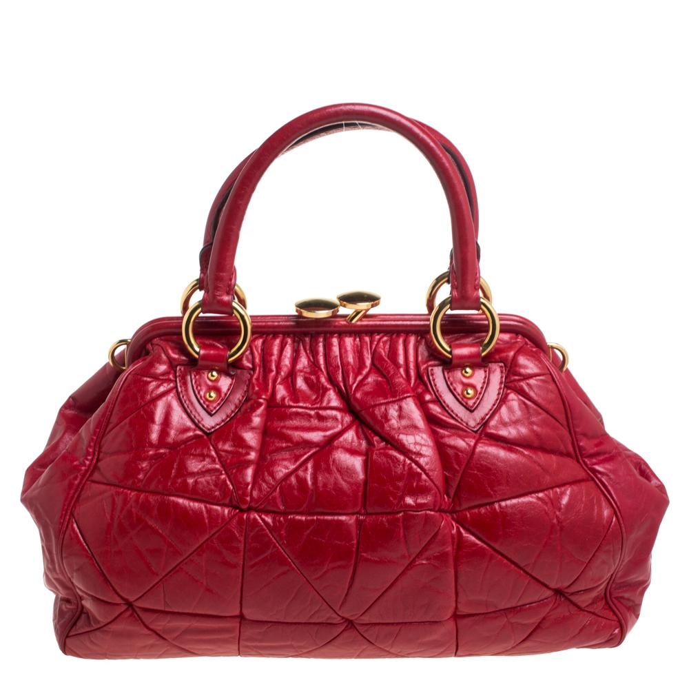 This Marc Jacobs design has a red quilted exterior crafted from leather and enhanced with gold-tone hardware. This elegant Stam bag features a kiss-lock top closure that opens to a fabric interior, dual top handles, and a removable chain that