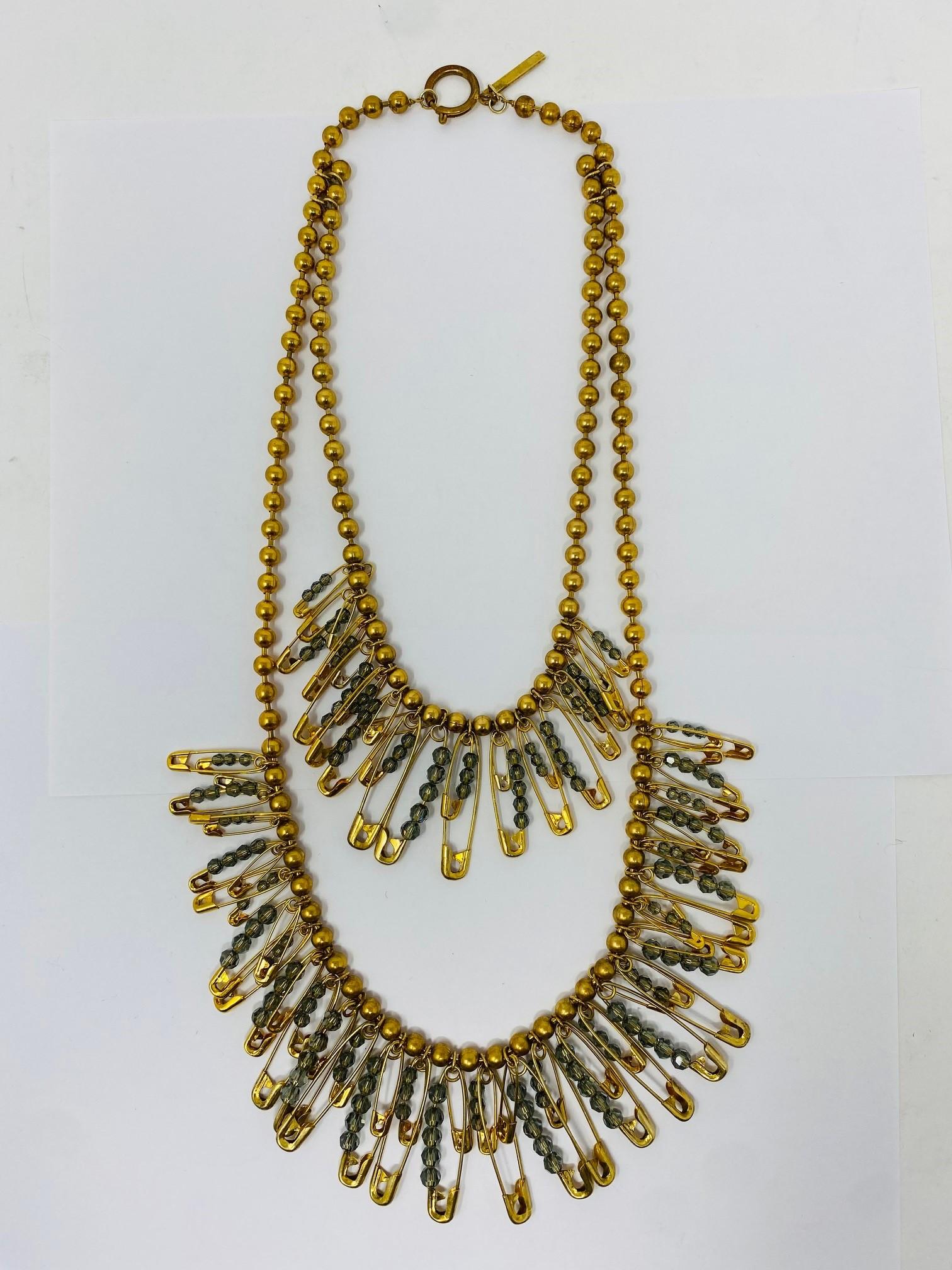 Beautiful and intricate jewerly piece by Marc Jacobs.  This incredible piece of jewerly is created in brass and crystals.  The gold tone juxtaposed with the gray-blue crystals in safety pins, adorned thru two staggered lengths are incredibly modern