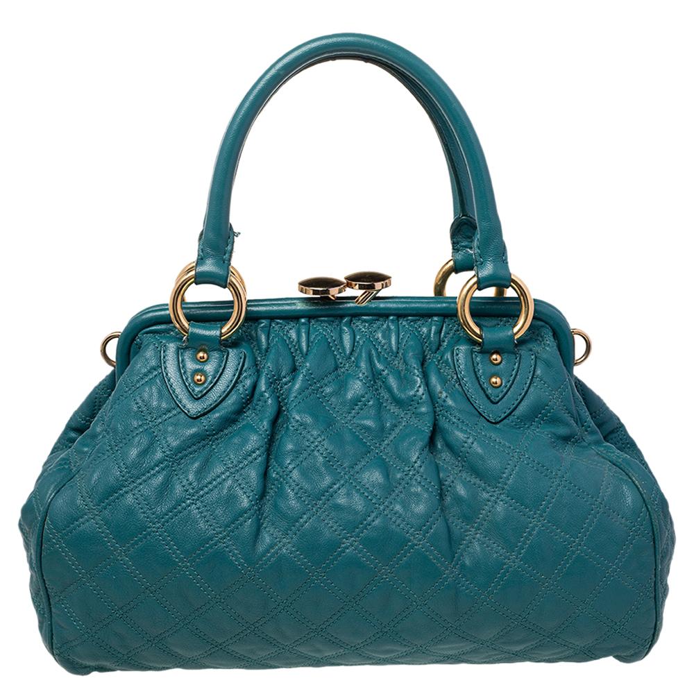 This Marc Jacobs design has a teal blue exterior crafted from leather and enhanced with gold-tone hardware. This elegant Stam bag features a kiss-lock top closure that opens to a canvas & leather interior, dual top handles, and a removable chain