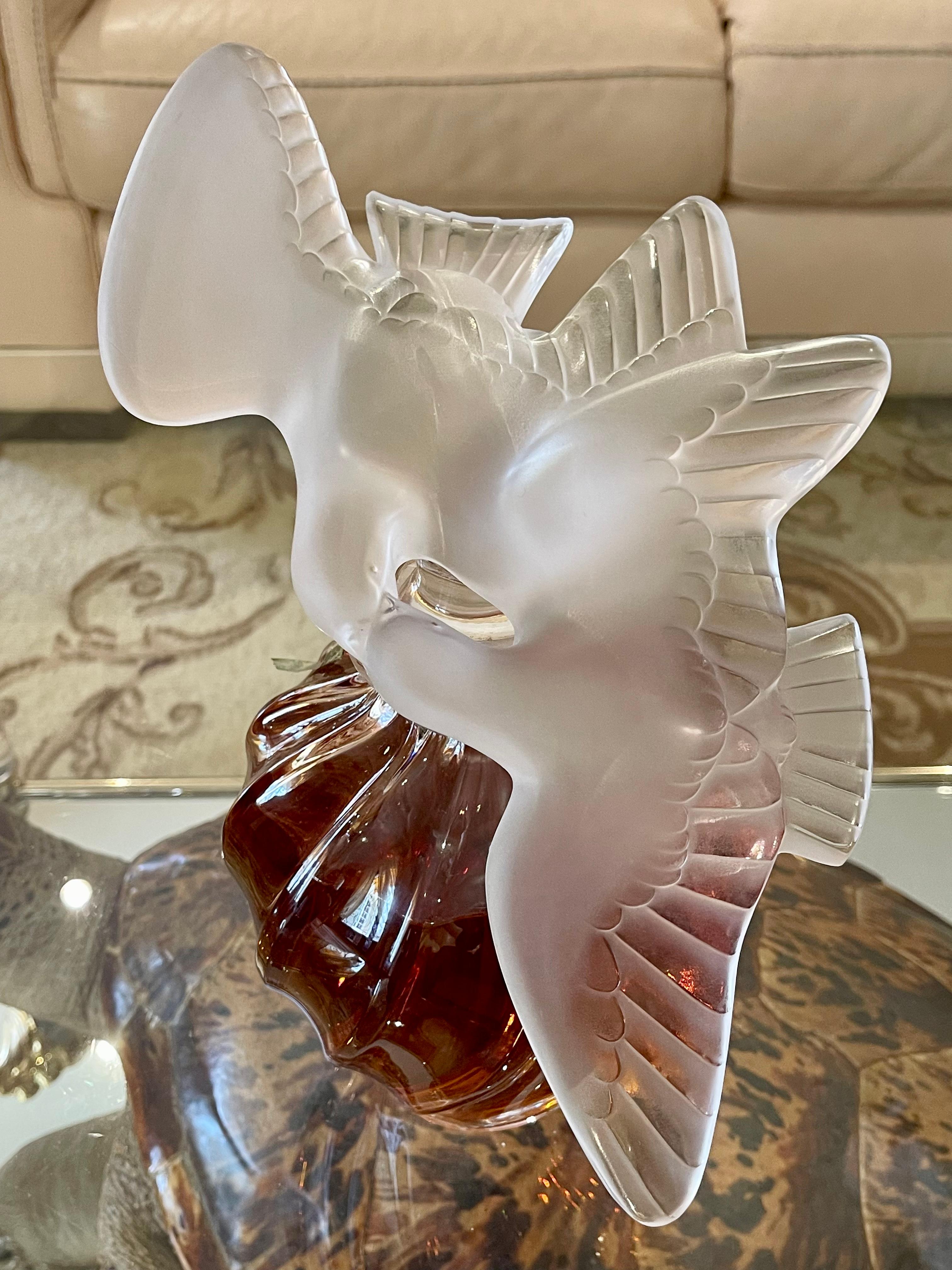 Large “Air du Temps” bottle with two doves in Lalique crystal created for Nina RICCI. This superb bottle contains intact Eau de parfum. Bottle in perfect condition with its original box.

Dimensions
Height 31.5cm
Bottle diameter 17cm