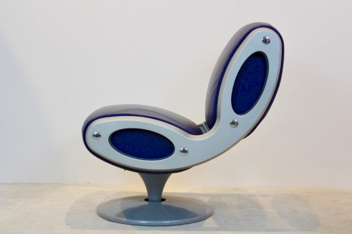Impressive ‘Gluon’ swivel chair designed by Marc Newson and produced by Moroso in the 1990s. Circular steel base with center cut from which rises the barrel supporting the seat, silver tinted polyurethane, blue leather trim. The Gluon chair was