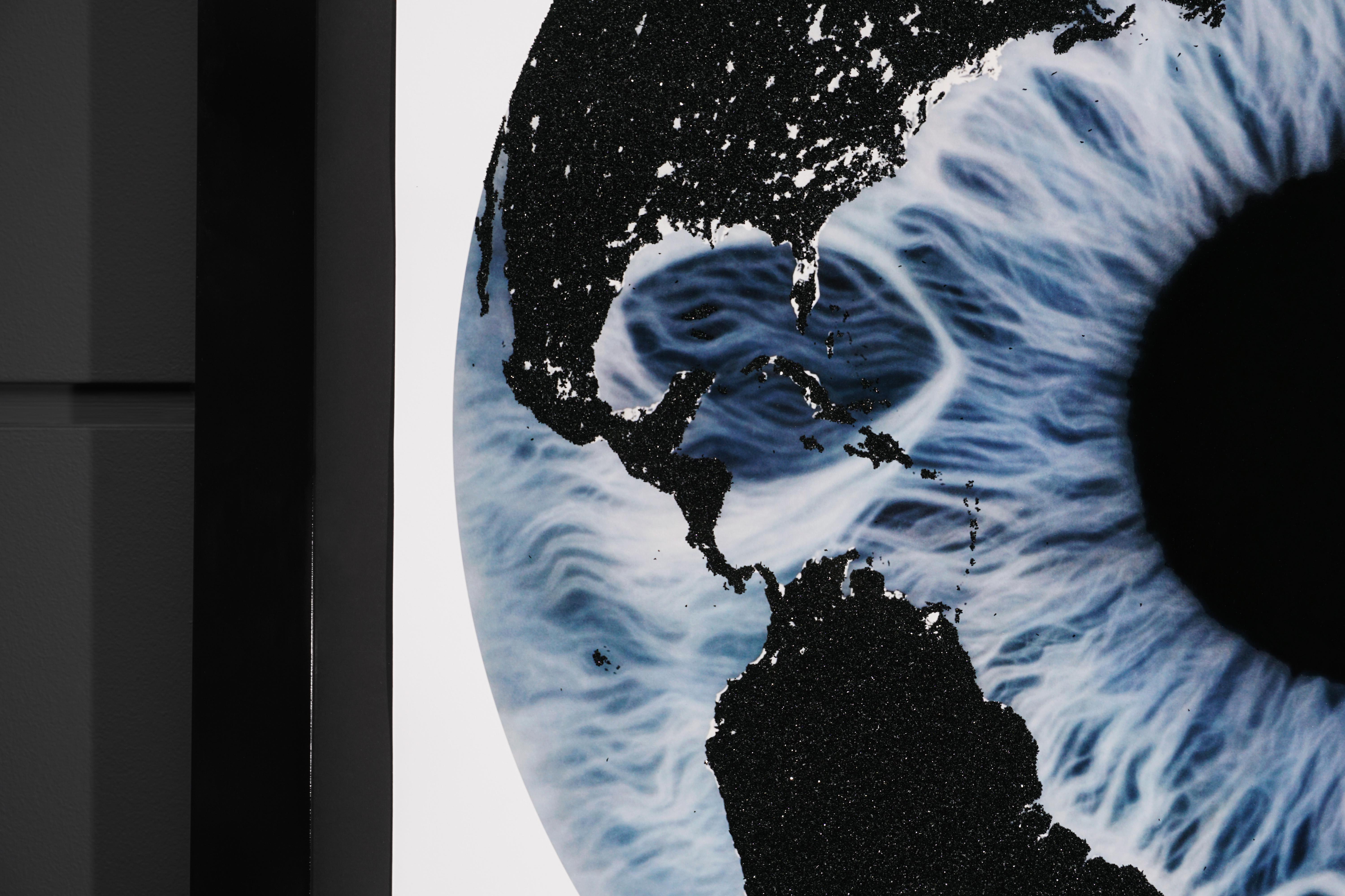 The 'Iris' with Diamond Dust is a silkscreen print on paper created in 2019 by Marc Quinn. The piece features a mystical blue iris with a glittering black diamond dust overlay in the shape of the earth's geography. This signed print is of an