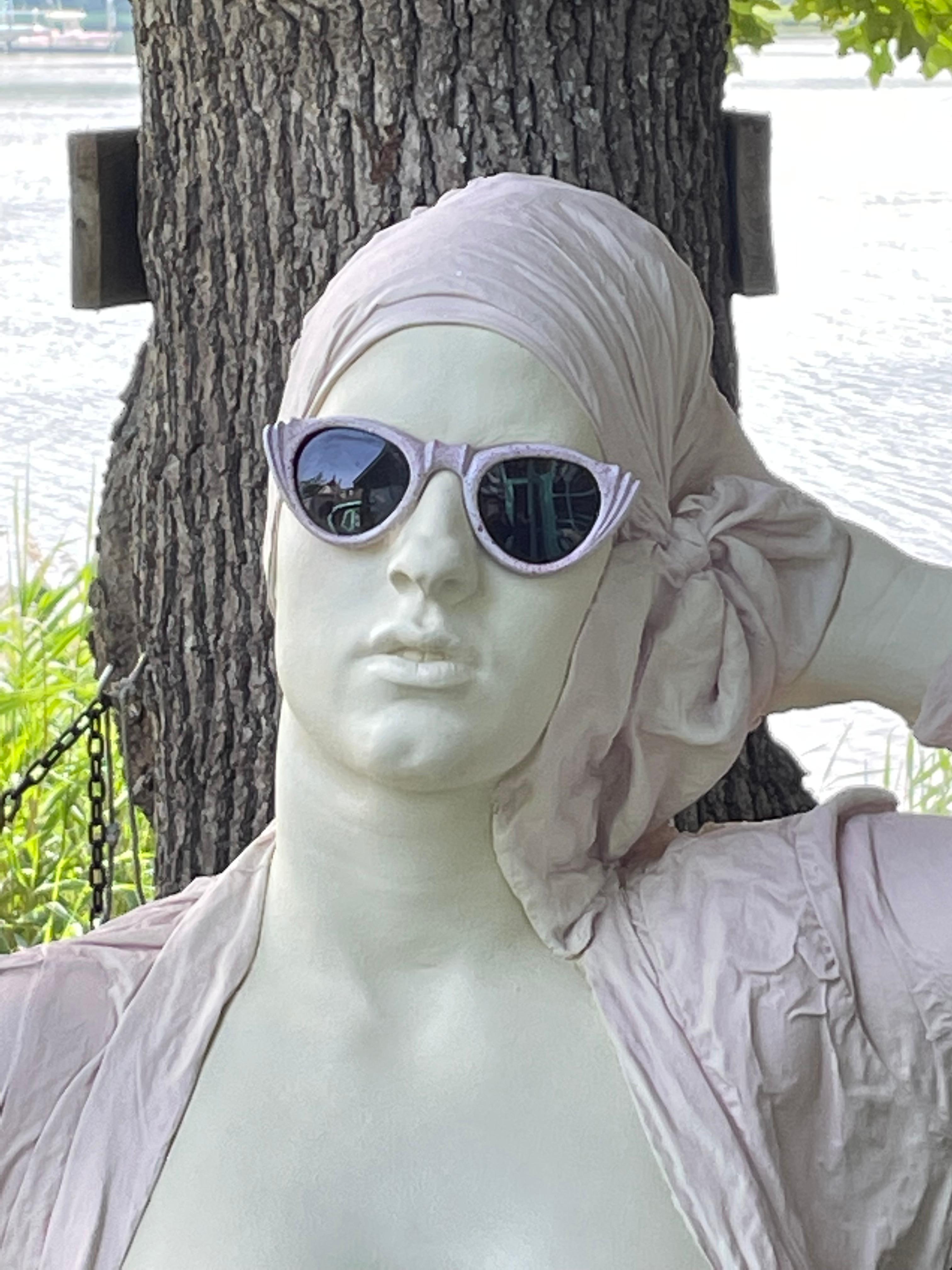 Wonderful and whimsical sculpture made by Marc Sijan .Sijan’s work is found all over the world. His art form is called Hyper Realism. This piece is a lifelike ceramic sculpture of a woman in a bathing suit and sunglasses. Hang her on a wall or give