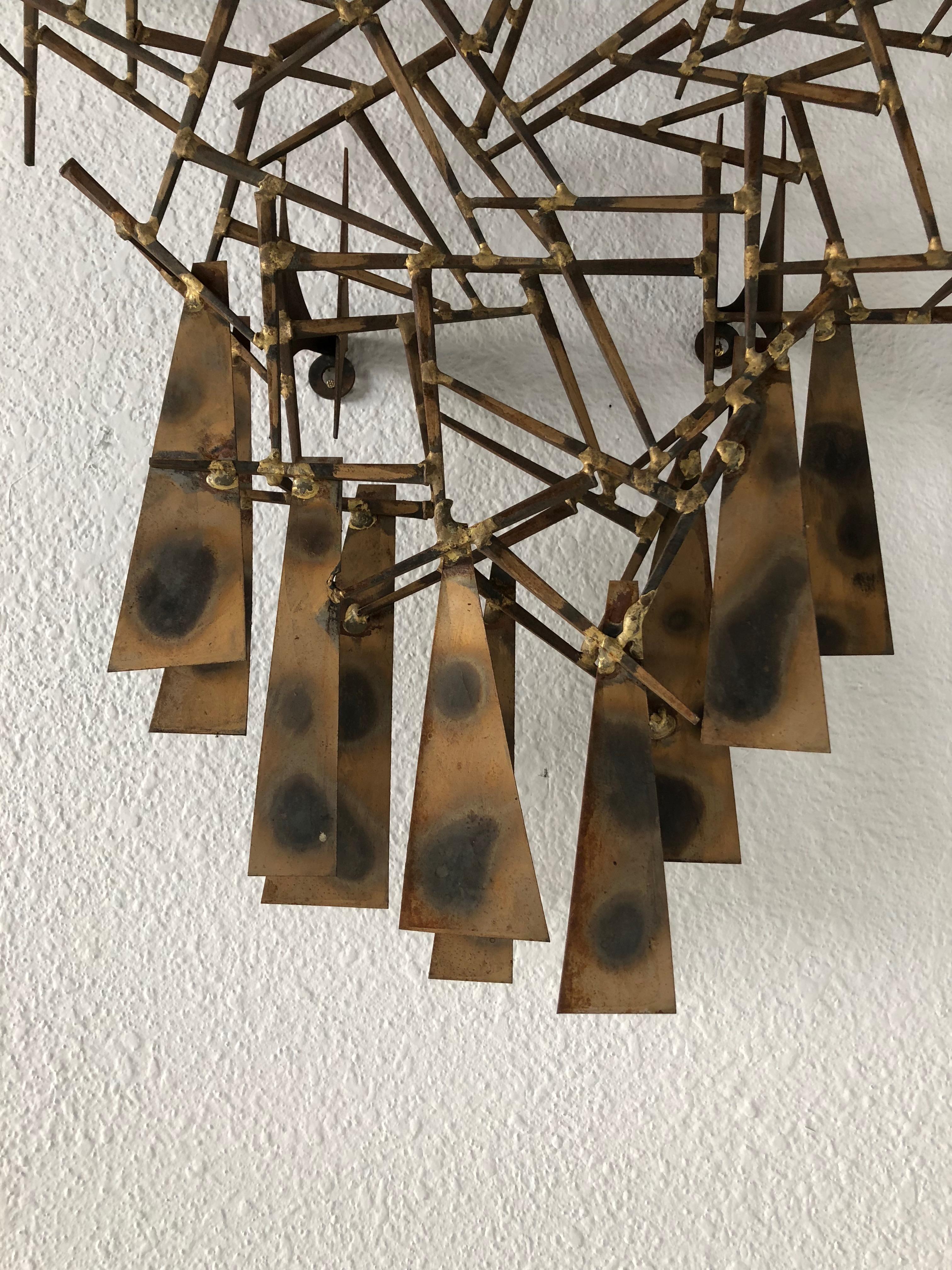 This handmade nailhead wall sculpture by Marc Weinstein of Marc Creates has nice brass and blackened finish to the metal and nails. There are four wall mounts and the sculpture could be mounted with the top up or down.