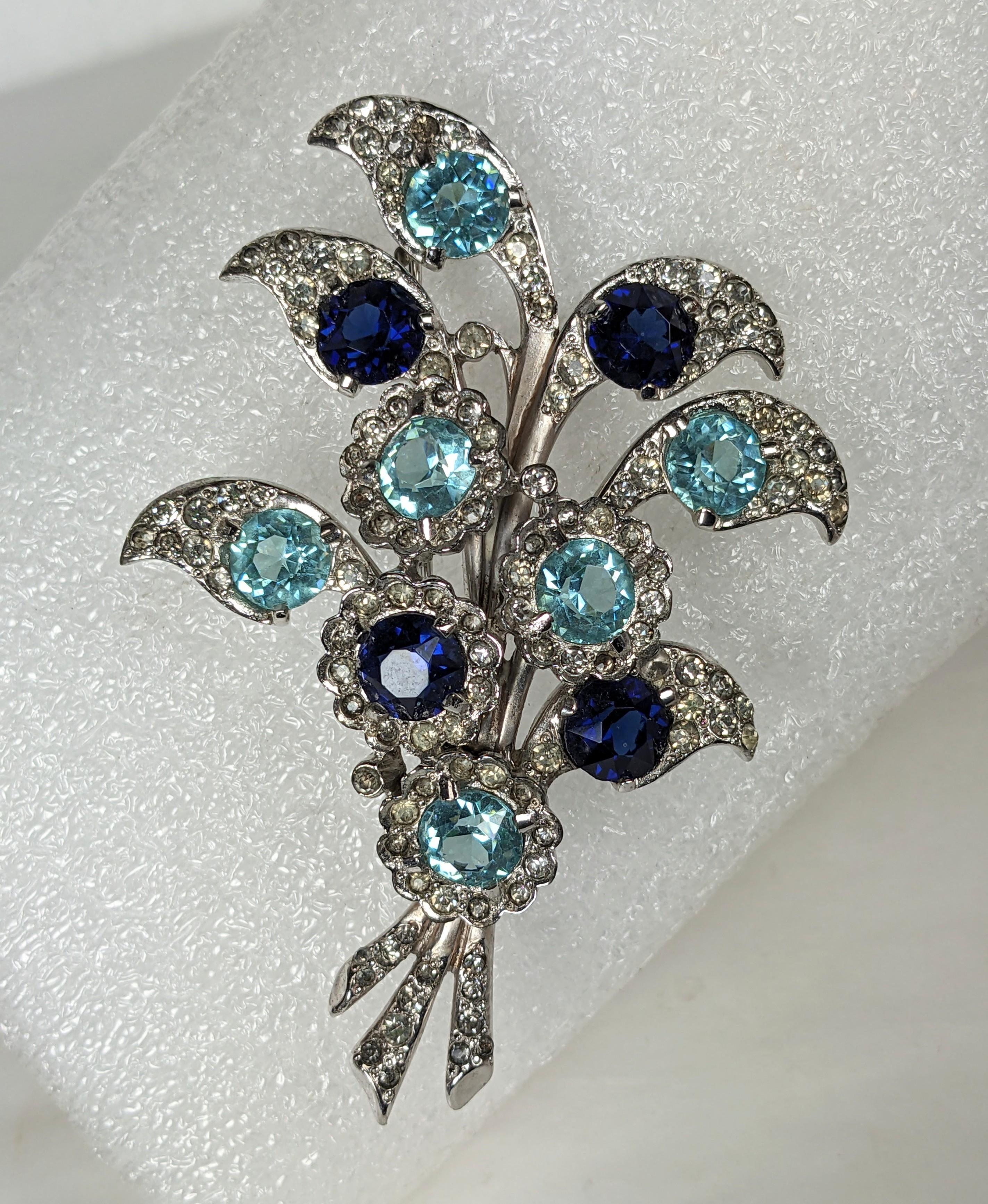 Marcel Boucher leafy floral spray brooch of crystal rhinestone pave, faux aquamarine and sapphire round chatons set in rhodium plated base metal, 1940s USA. Excellent Condition. 
Marked: MB (phrygian cap), 3.50