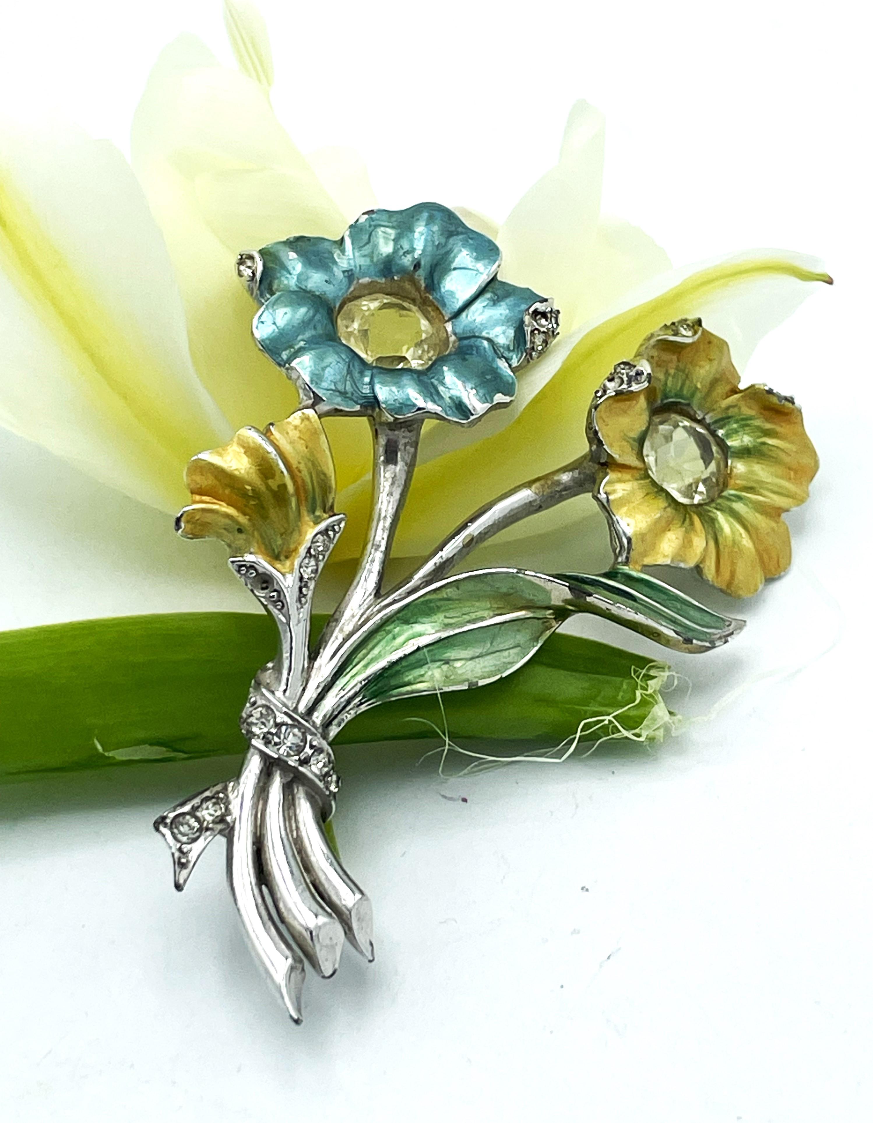 Brooch with 2 flowers by Marcel Boucher, enamelled in light blue and yellow, a large cut rhinestone as a pistil.

Dimenstions:
Height 7cm
Width 5cm
Diameter of the 2 flowers approx. 2 cm
About
Material rhodium-plated metal and rhinestones
Signed MB,